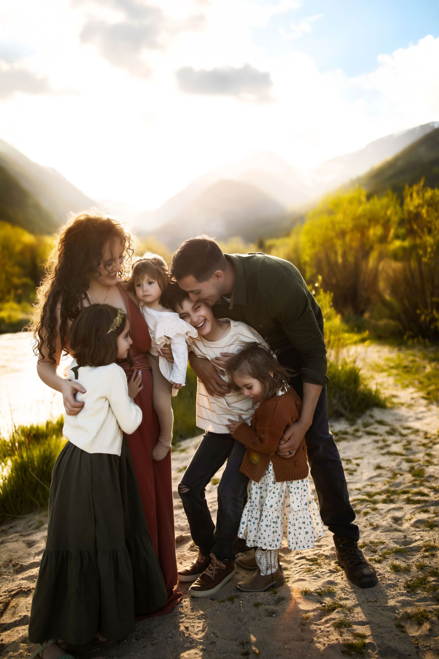 A family shares tender moments together on a sunlit beach path during golden hour.