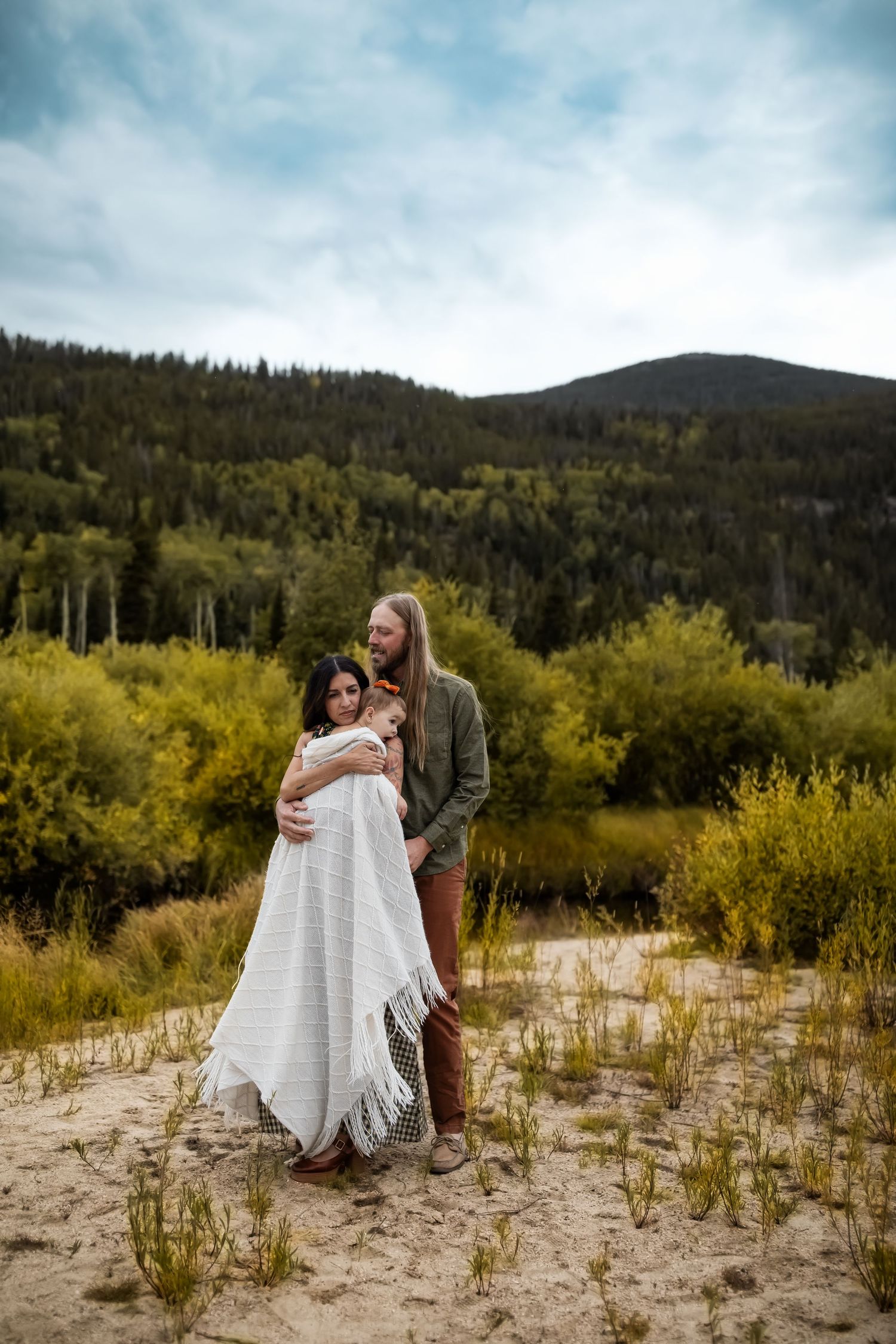 A romantic scene unfolds with a white blanket in a mountain valley setting.