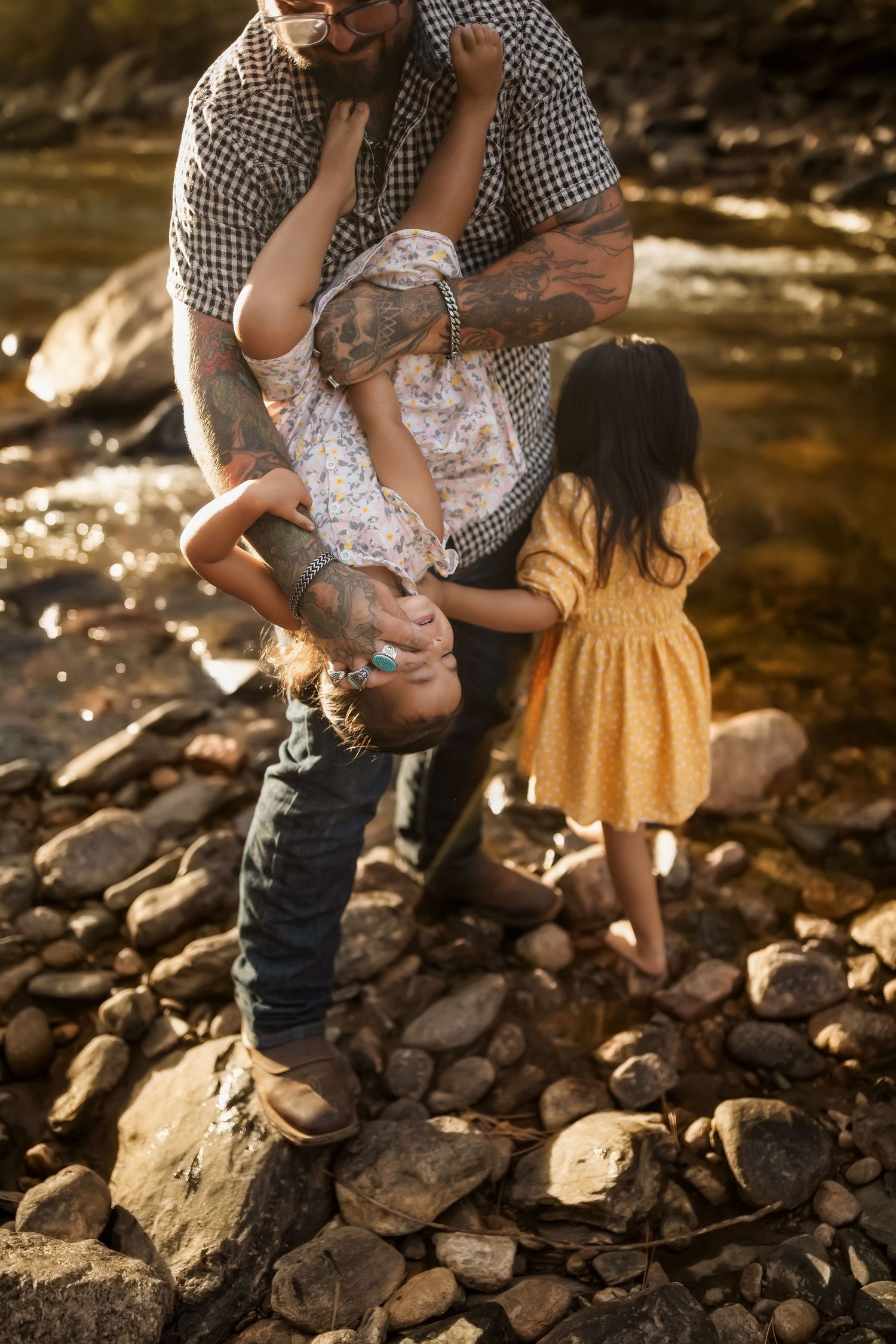Parent and child share a tender moment while sitting on rocky ground in warm sunlight.