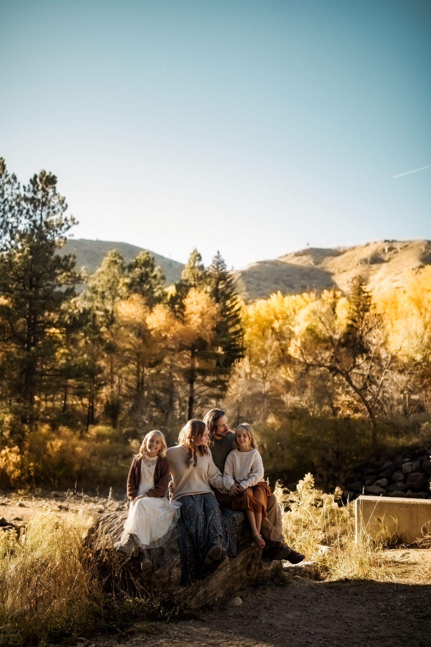 Group gathered on hillside during golden hour with mountains in background.