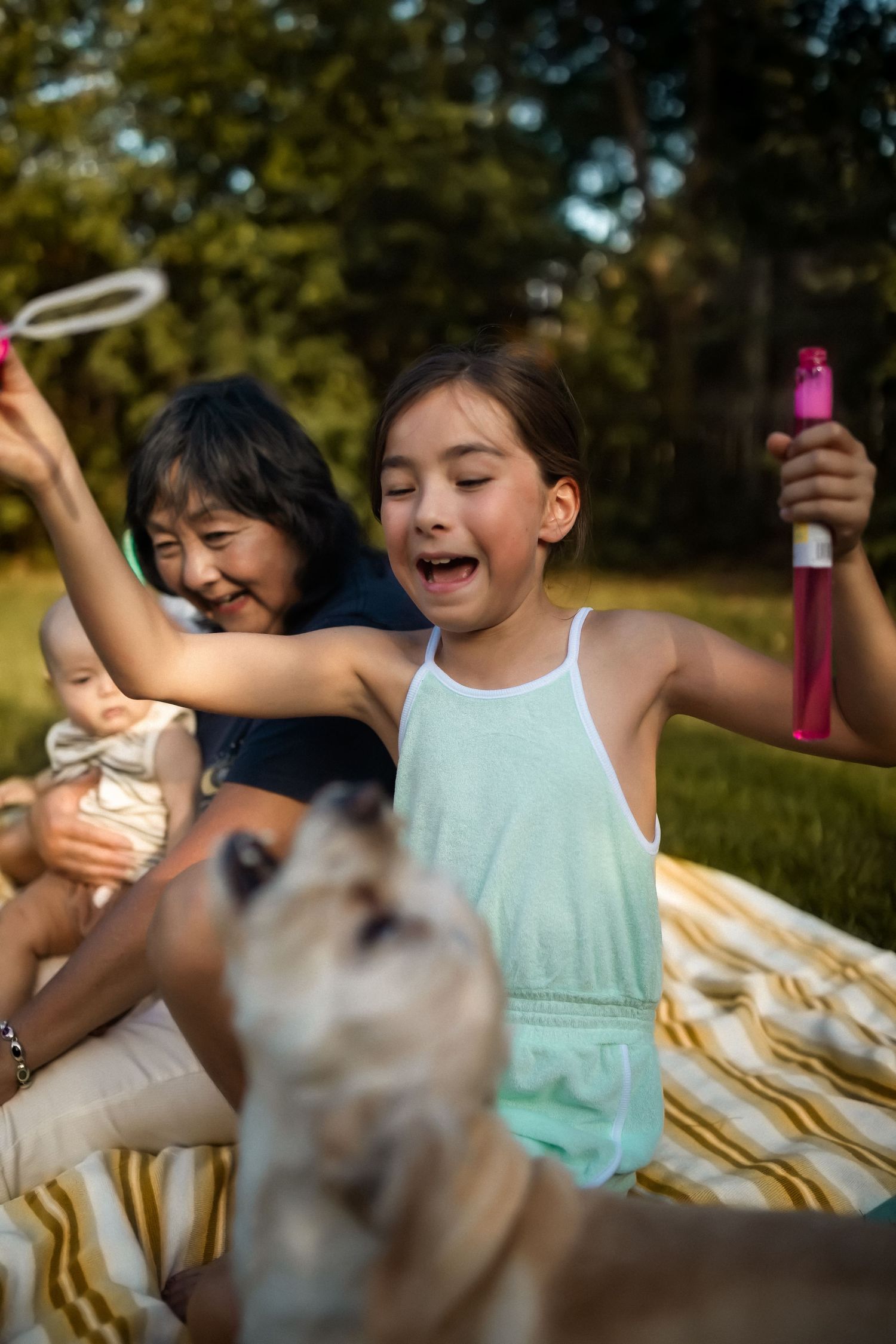 Children play together outdoors on a sunny day while blowing bubbles and enjoying summer activities.