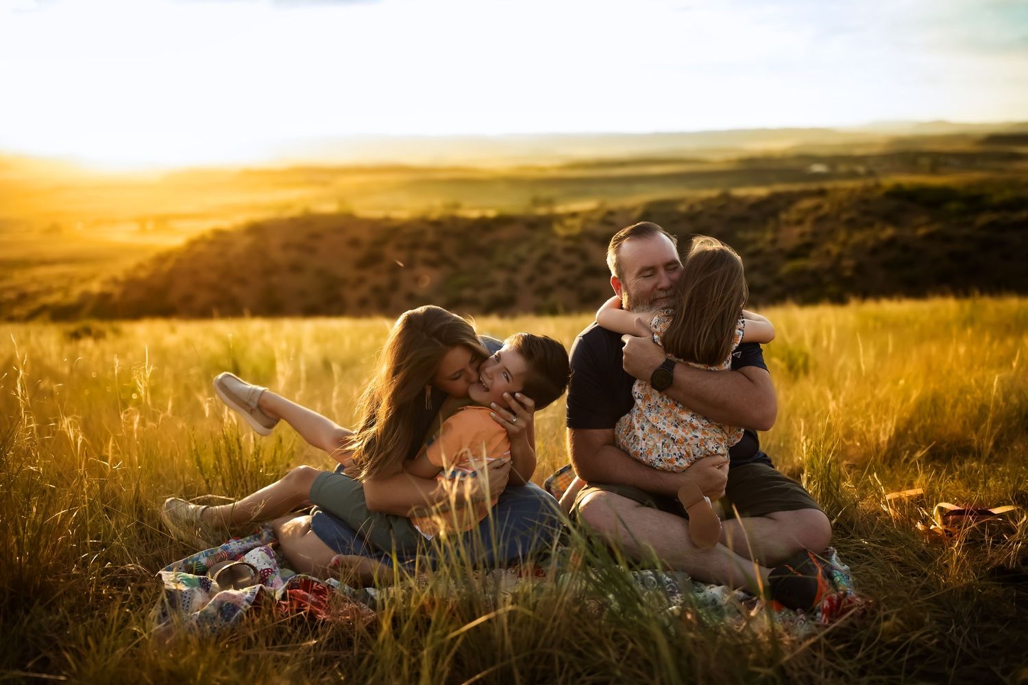 Family enjoying a relaxing moment together in a sun-drenched meadow at golden hour.