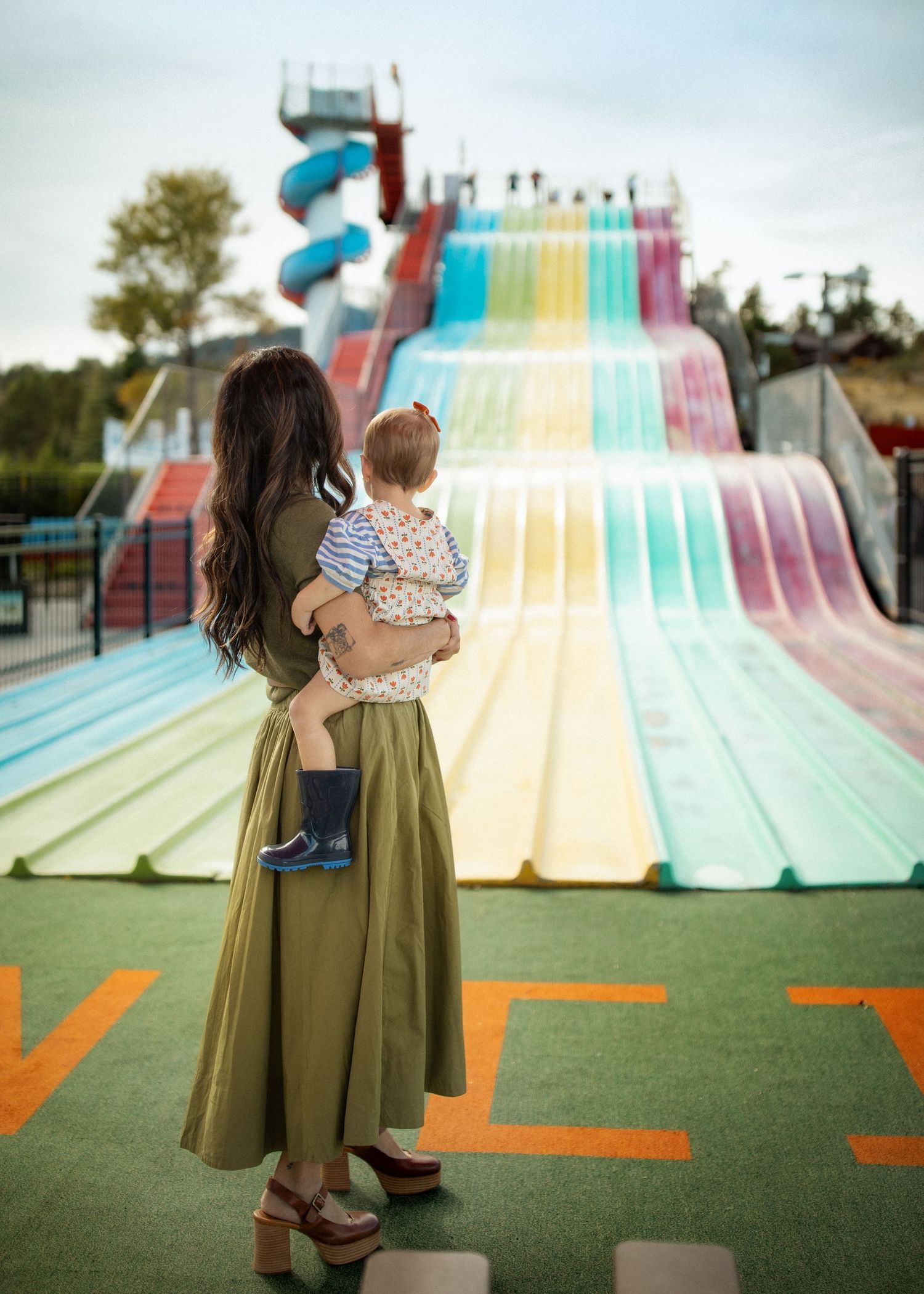 Colorful carnival slide with rainbow stripes on green turf.