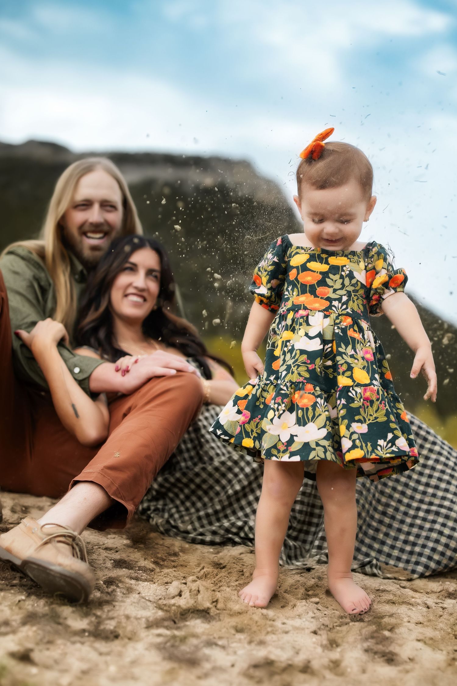 A playful moment captured on a sandy beach with floral and checkered patterns in view.