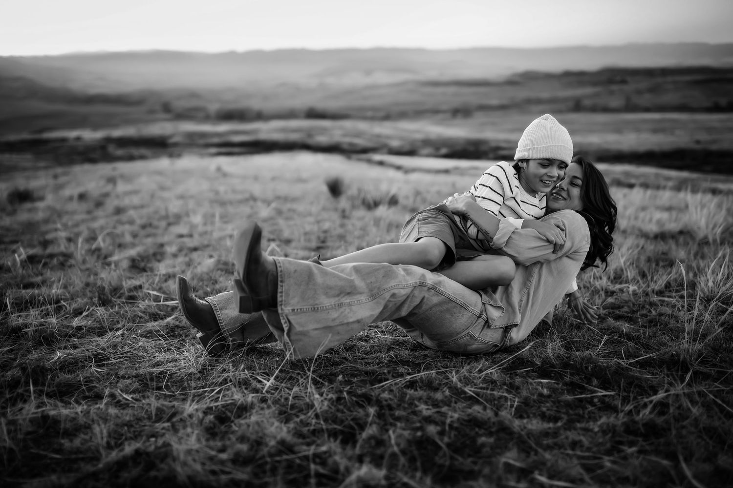 A series of black and white landscape photographs showing a person lying in grass fields at different angles.