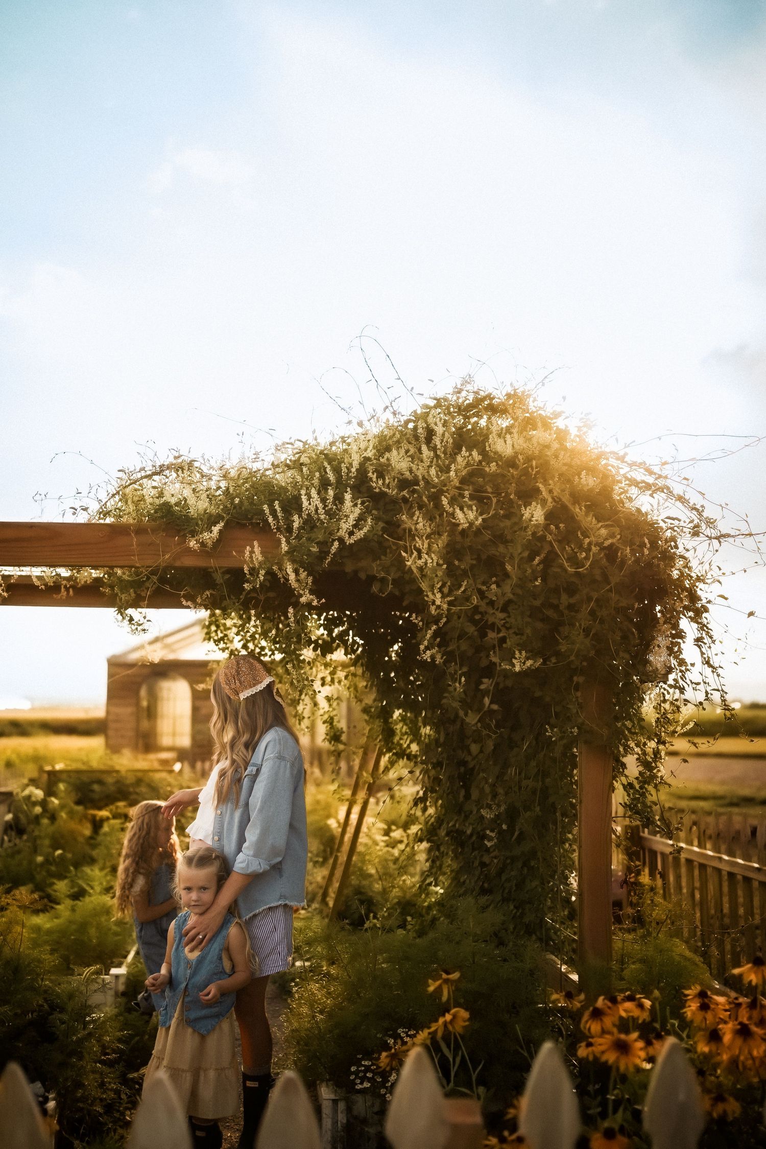 A couple enjoys a romantic sunset moment together in a garden with blooming flowers and climbing vines.