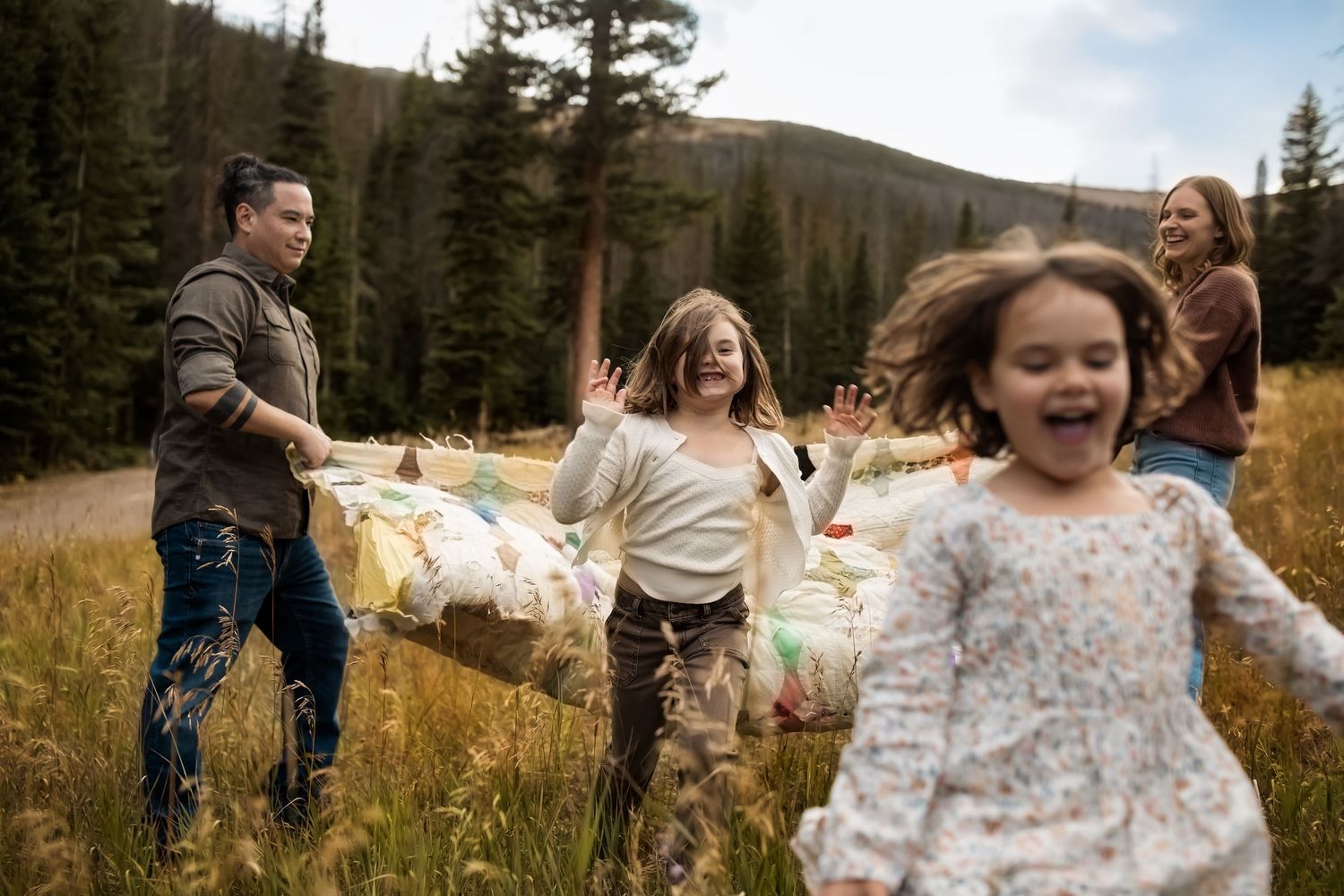 A joyful family plays together in a scenic mountain forest setting during golden hour.