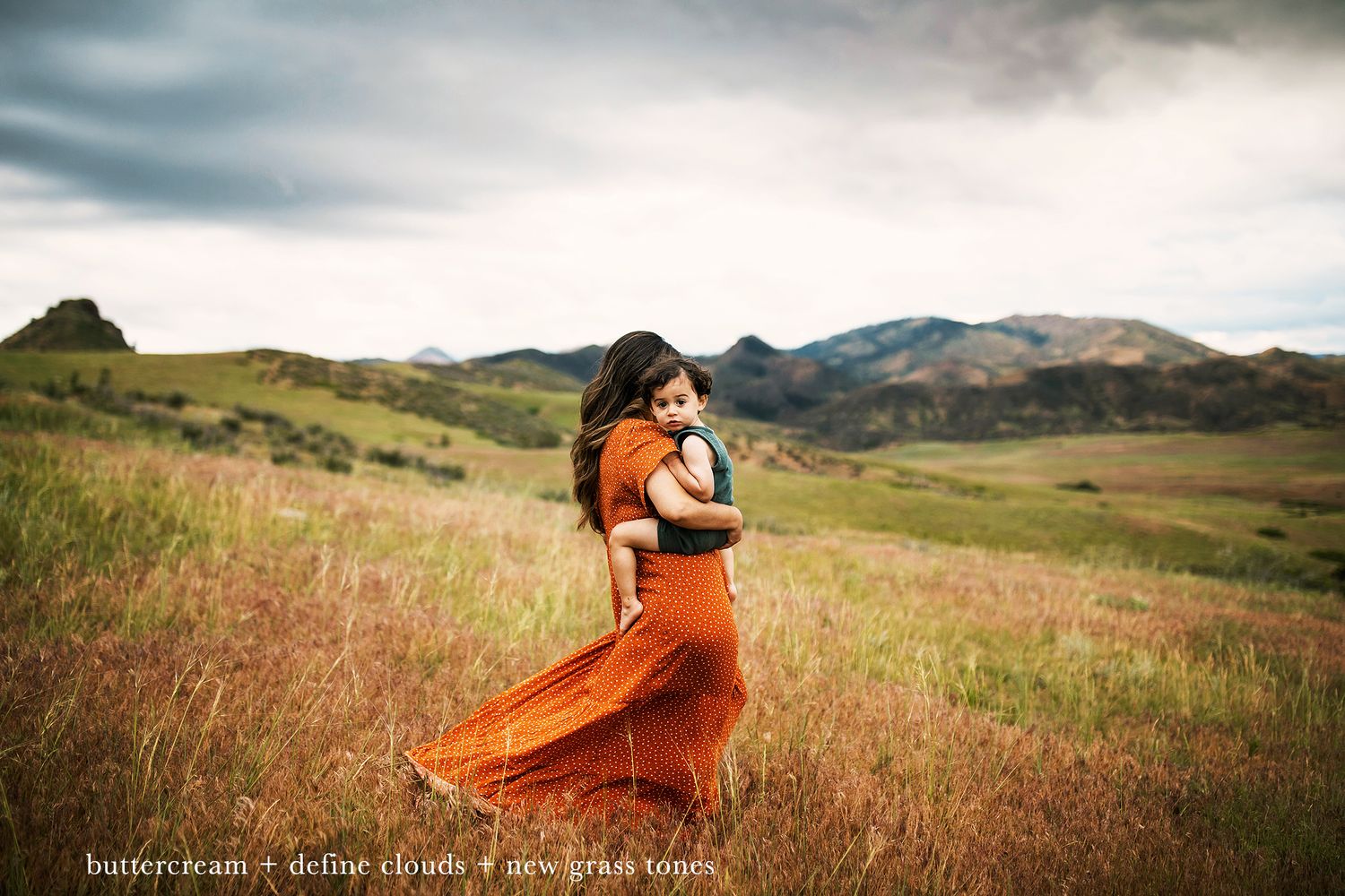 Person in vibrant orange dress twirling in mountain meadow under cloudy skies.