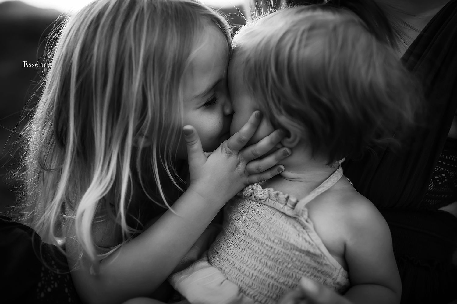 Intimate black and white portrait showing tender moments between children.