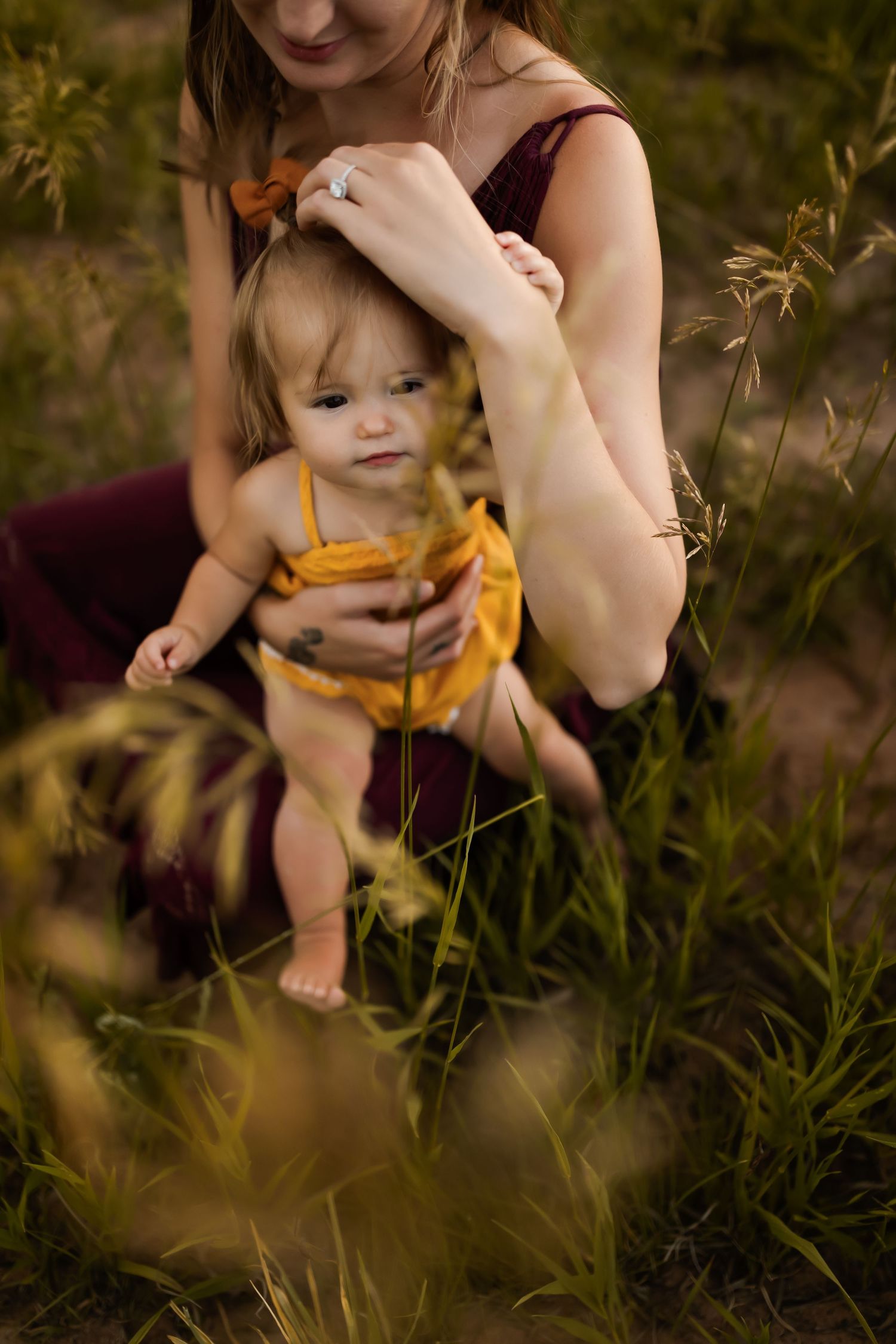 Tender moment captured in tall grass during golden hour.