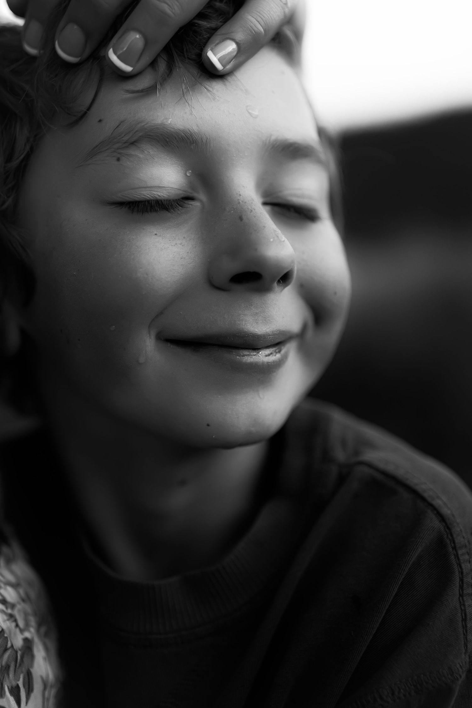 Close-up black and white portrait showing a gentle smile in soft lighting.