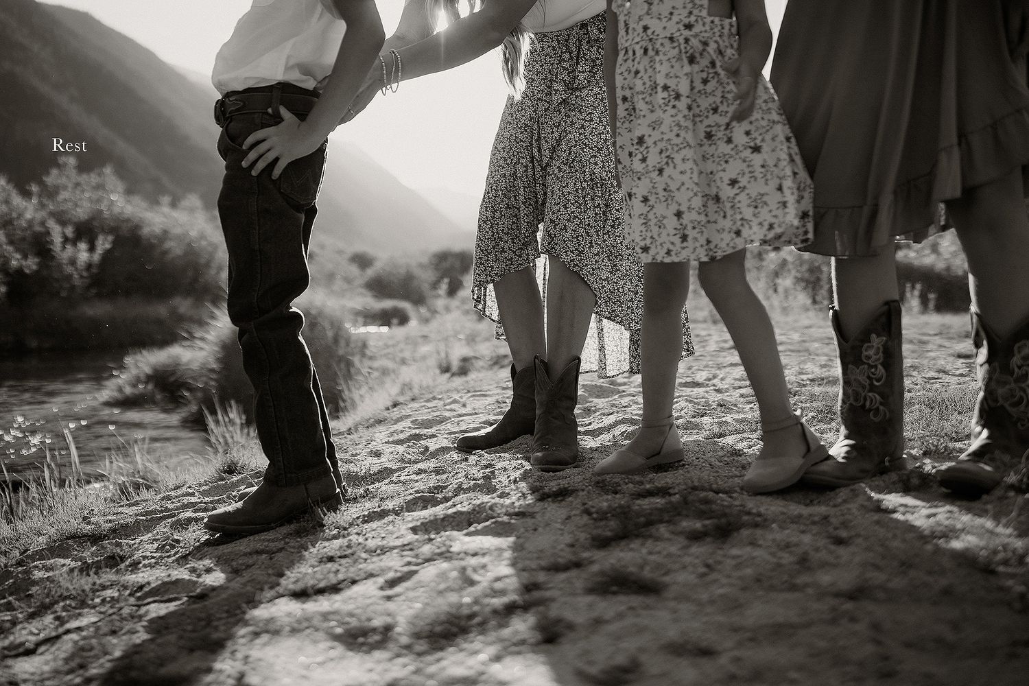 Low angle shot showing feet and legs of people standing in natural light on rocky ground.