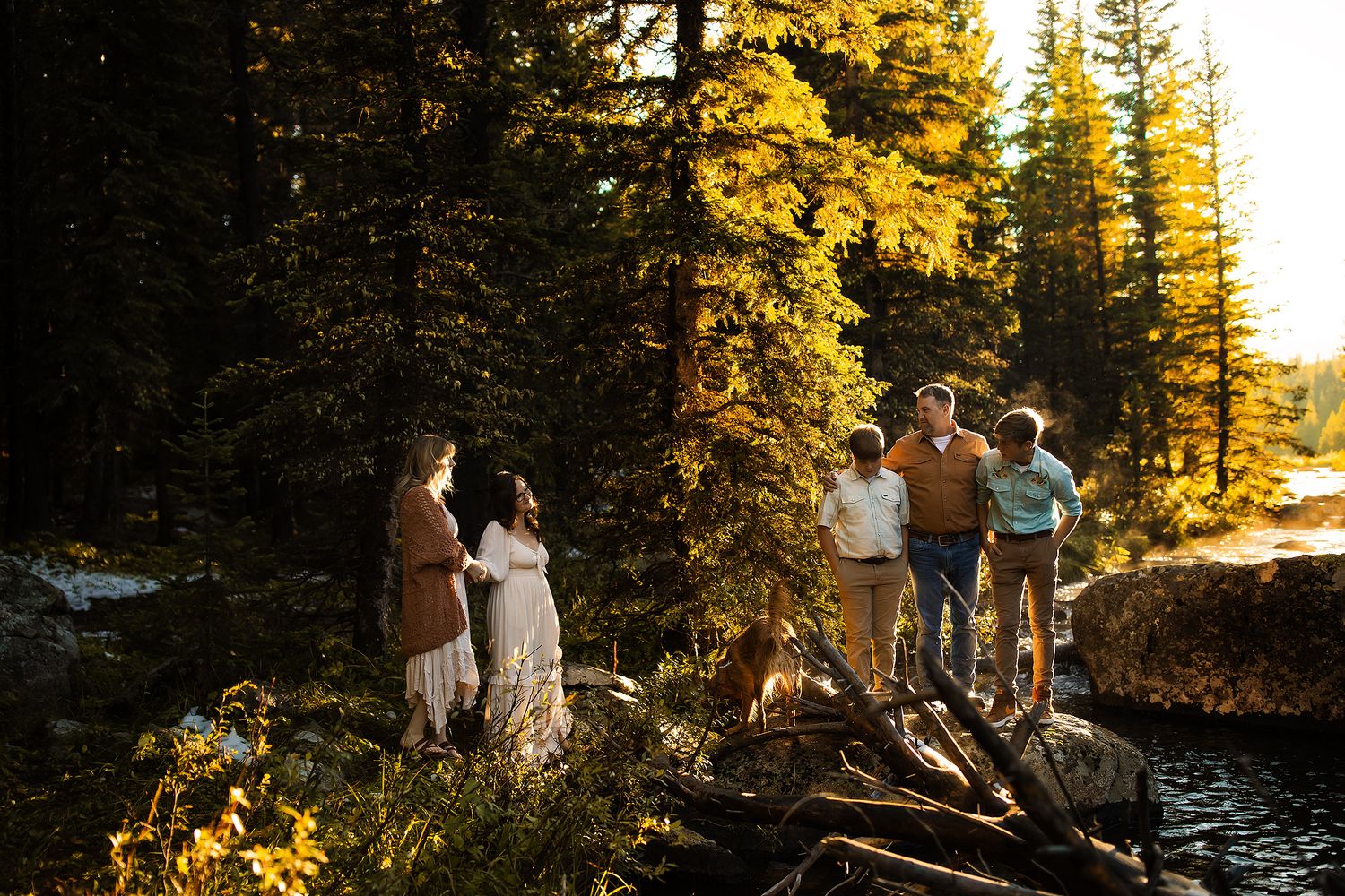 Group enjoying sunset by a lake surrounded by autumn trees in golden light.
