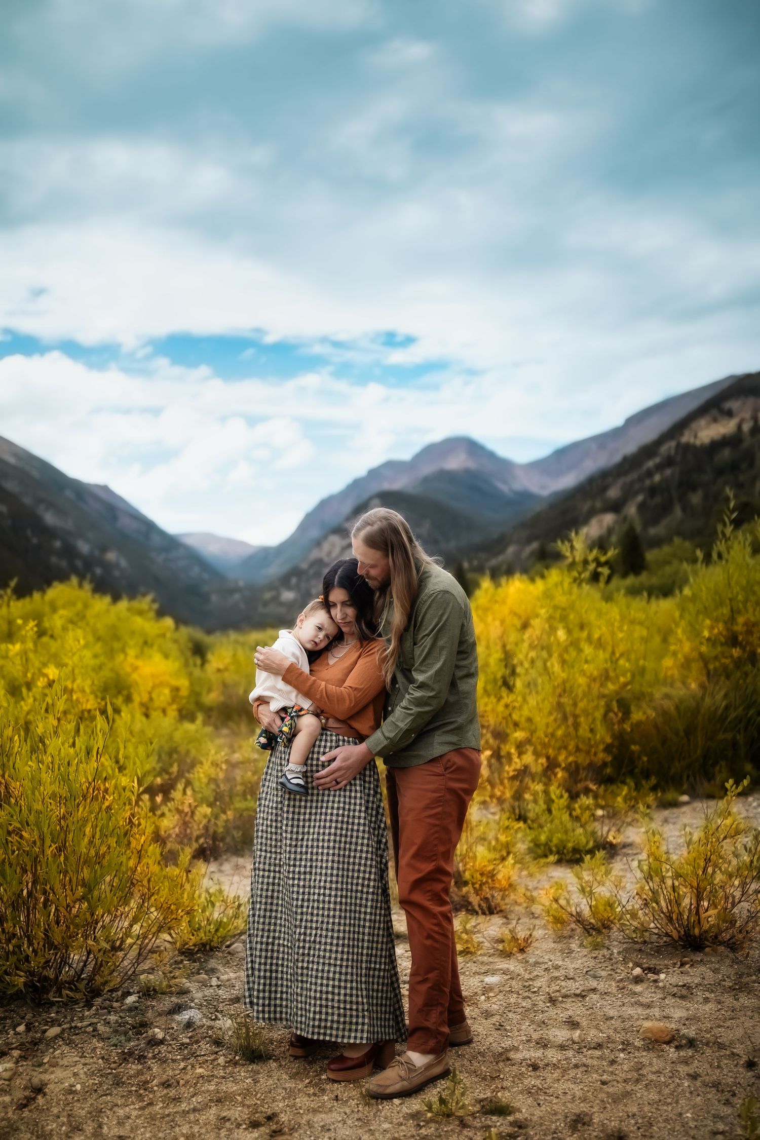 An intimate family moment captured in a mountain valley with golden autumn foliage.