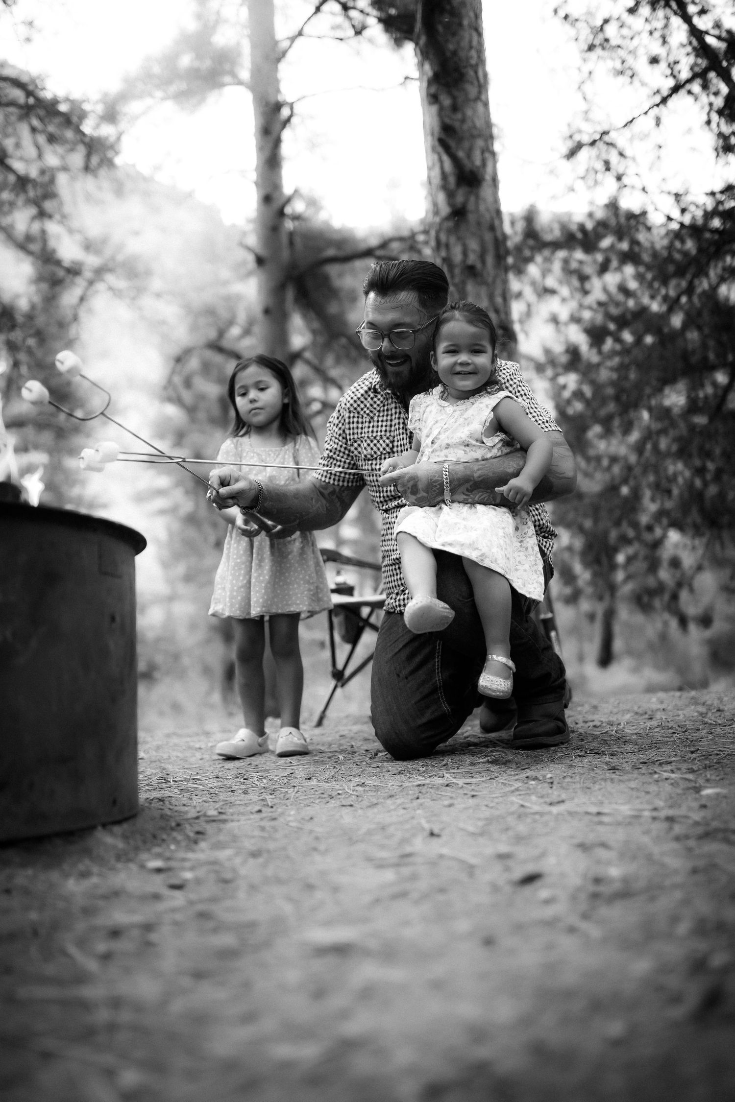Black and white image of a family enjoying a quiet moment together in a wooded setting.