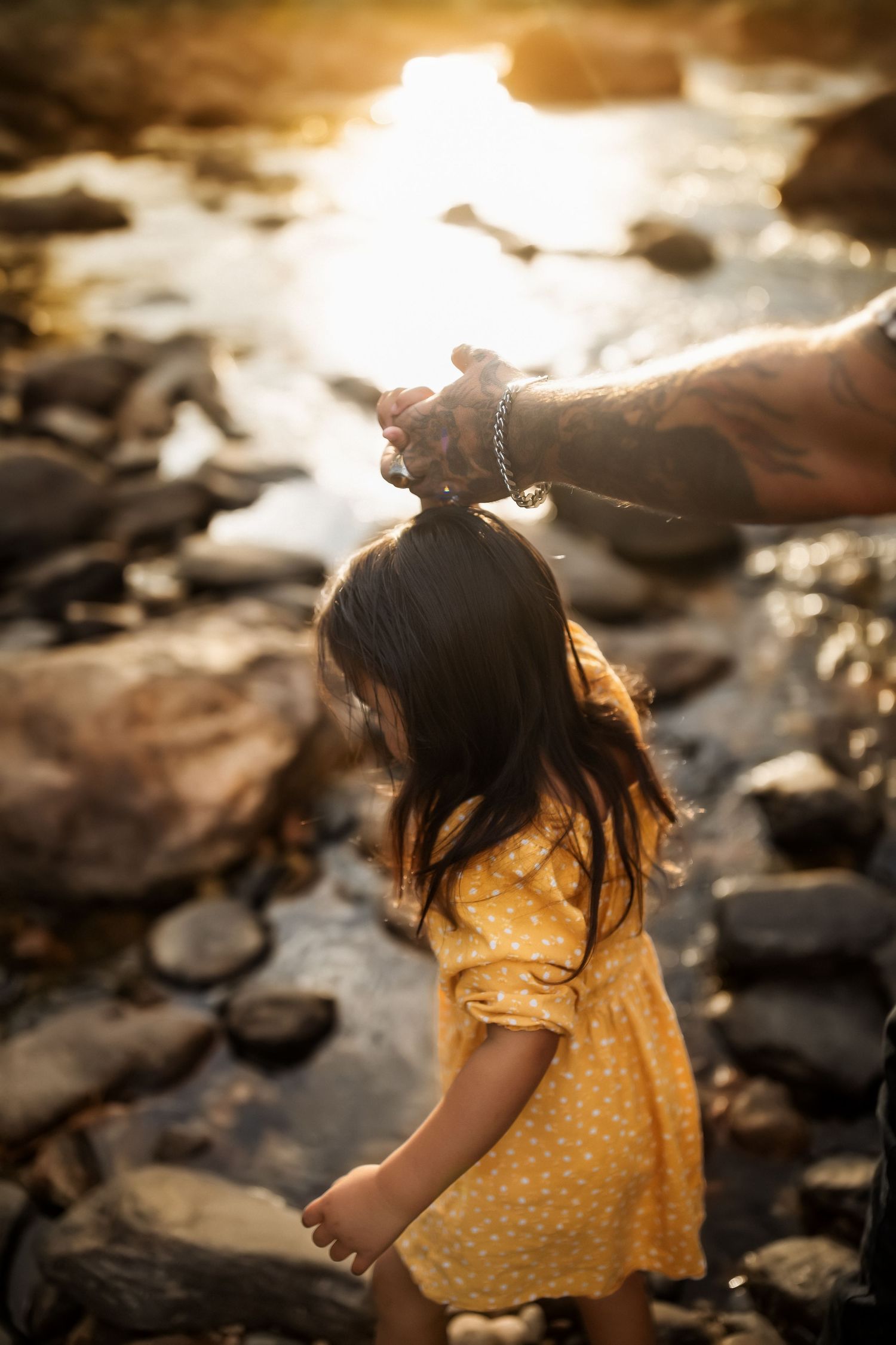 Silhouette of a child in yellow polka dot dress against golden sunset light.