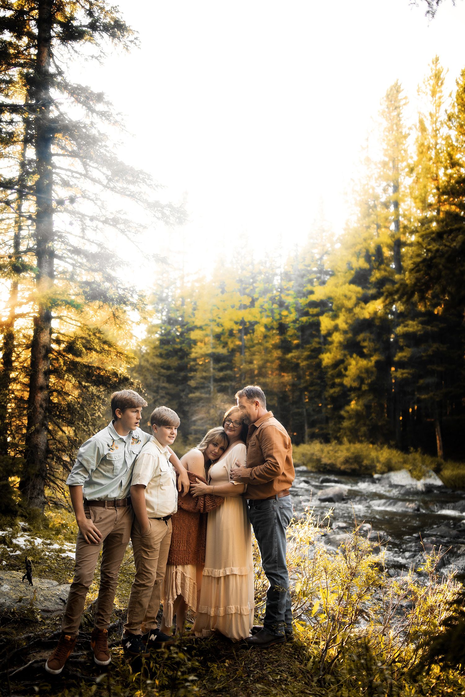 Group portrait in a forest setting during golden hour with sunlight streaming through pine trees.
