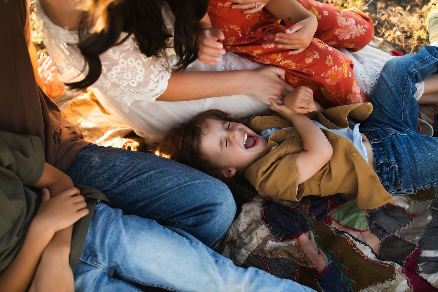 The image shows a group of people, including a woman in a white dress, lying on a couch covered in colorful blankets and pillows.