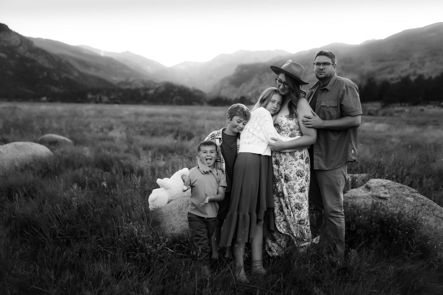 Panoramic view of a family gathering in a mountain meadow at sunset.