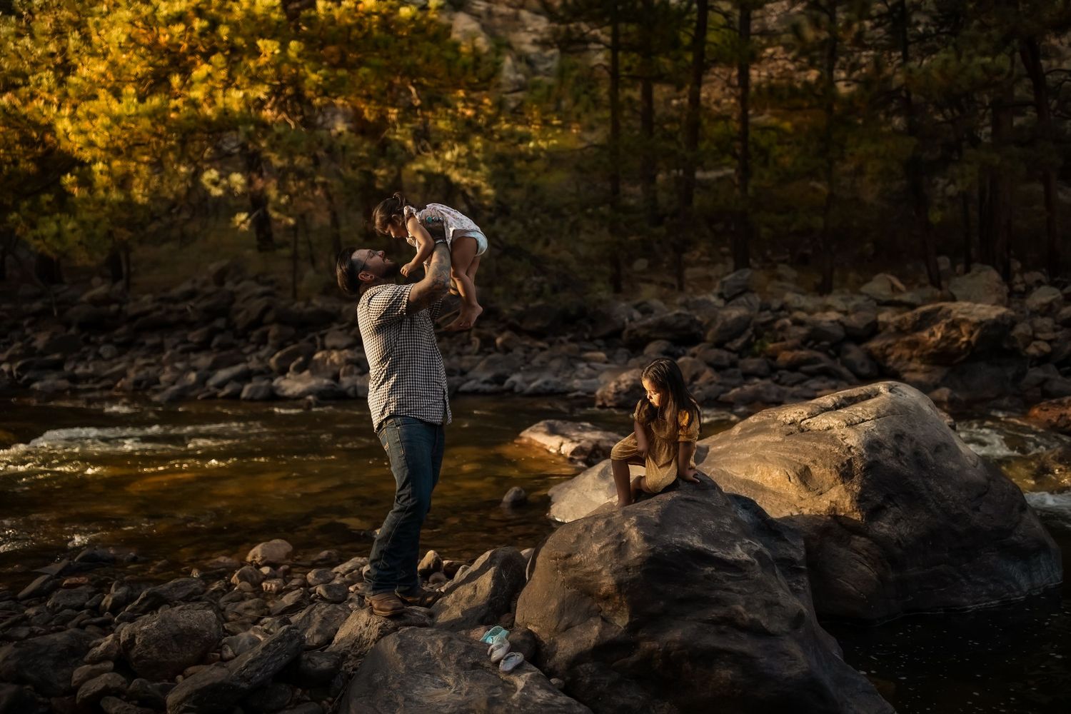 Family exploring rocky terrain during sunset with pine trees in the background.
