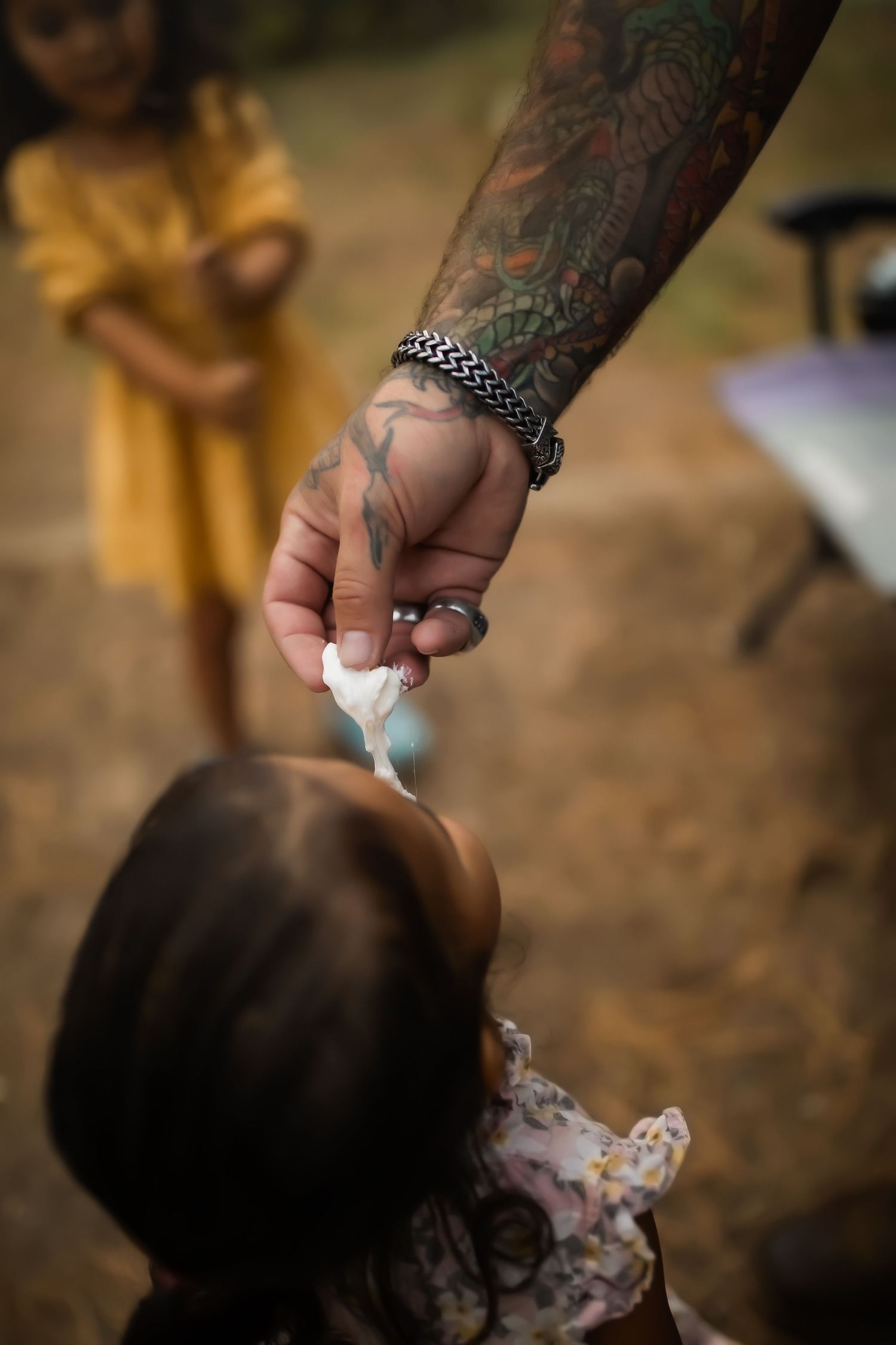 Tattooed hand reaching out to touch someone's hair in warm sunlight.