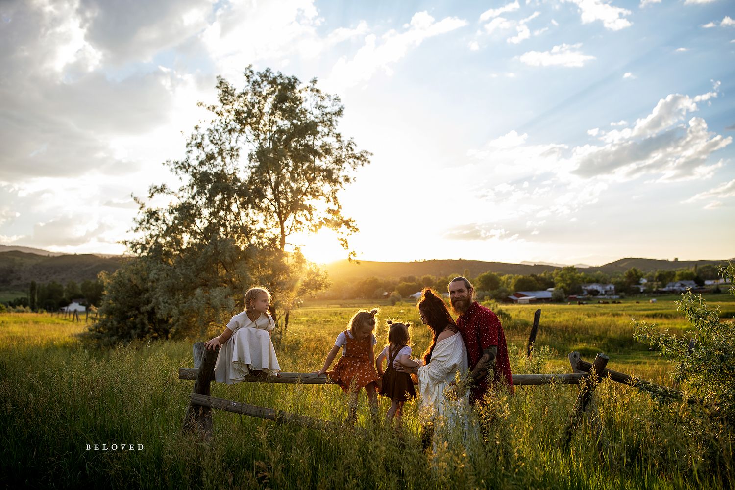 Family gathering in a golden meadow at sunset with mountains in the background.