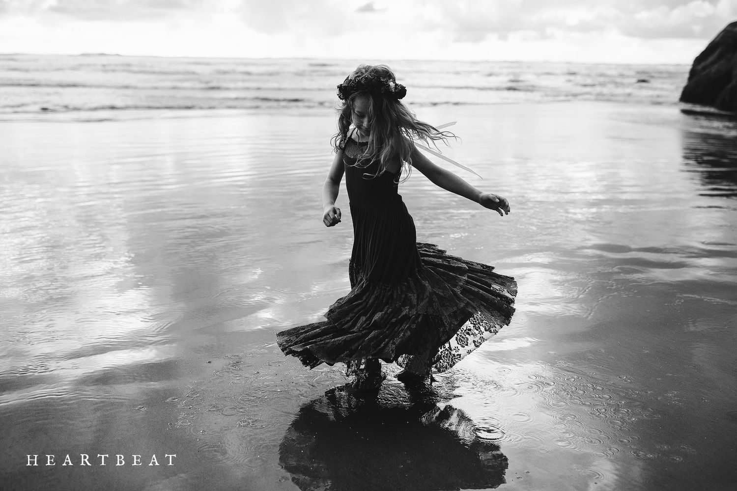 People dancing and splashing in shallow water on a misty beach.