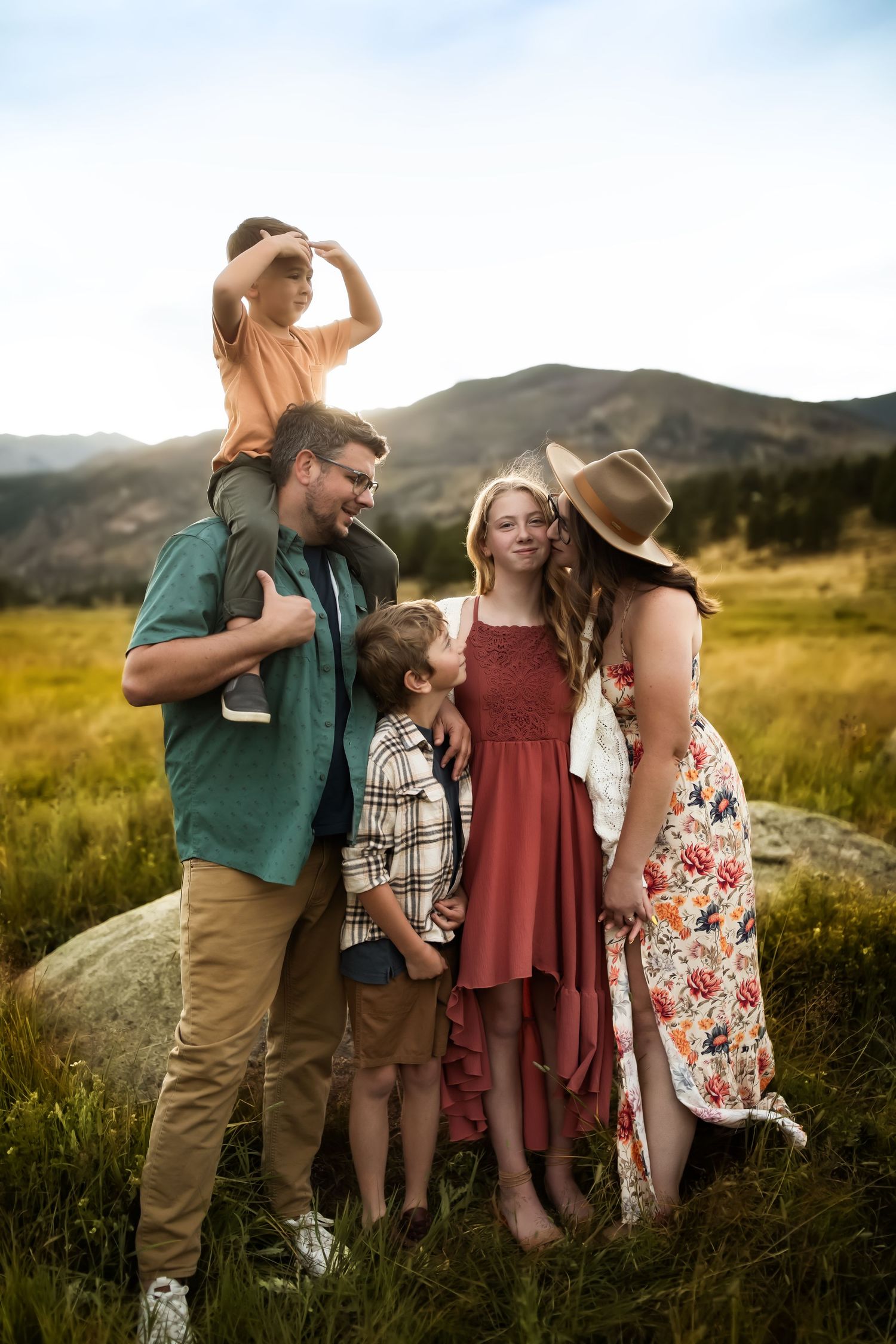Family enjoying a playful moment together outdoors in a golden field during sunset.