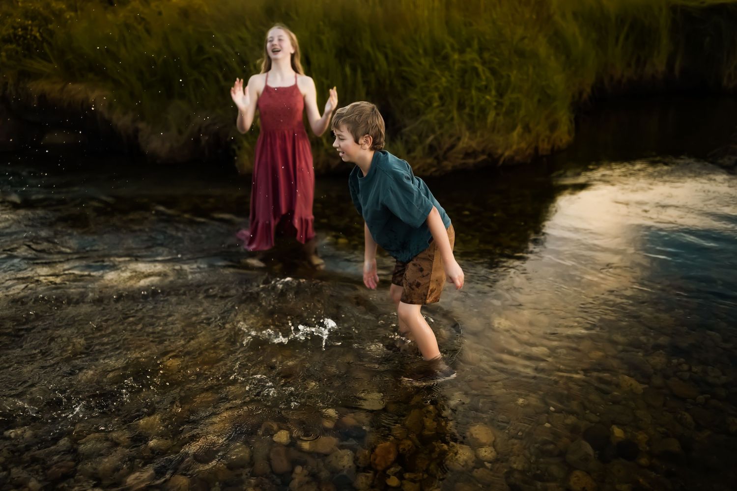 People wading and splashing in a mountain stream during golden hour.