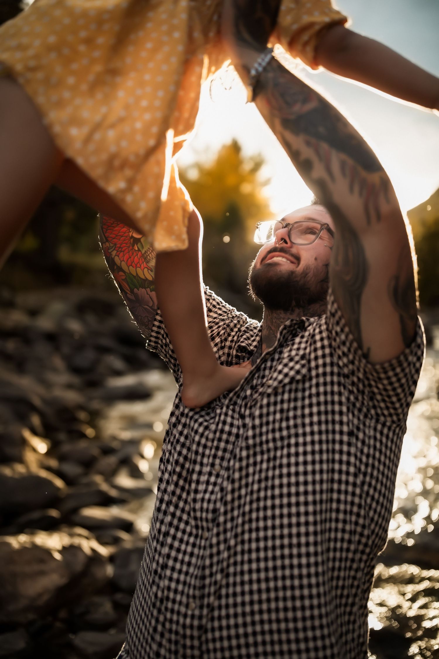 Person in checkered shirt holding fabric up against bright sunlight on rocky terrain.