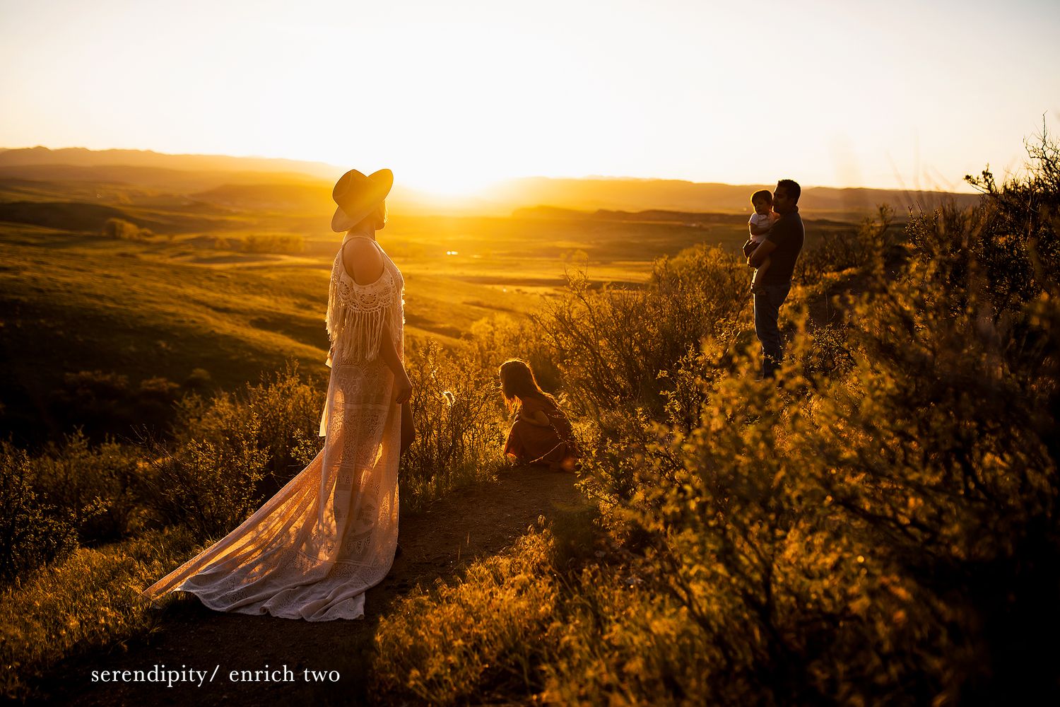 Silhouettes of people walking along hilltop against dramatic sunset sky.