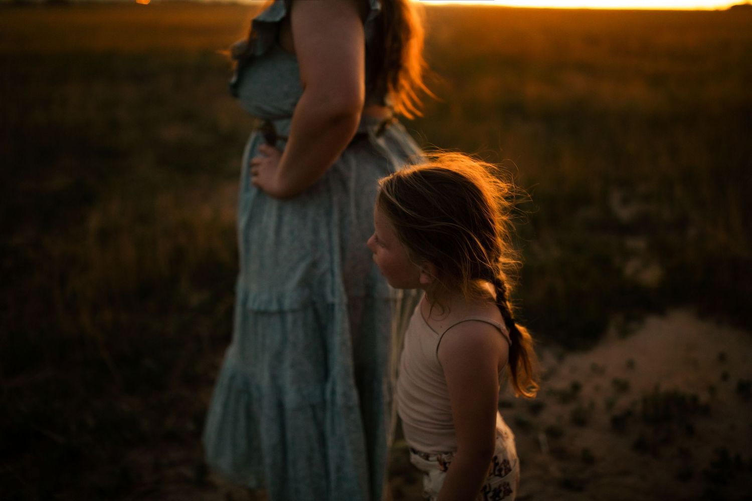 Silhouettes of people walking through a field at sunset with warm golden light.