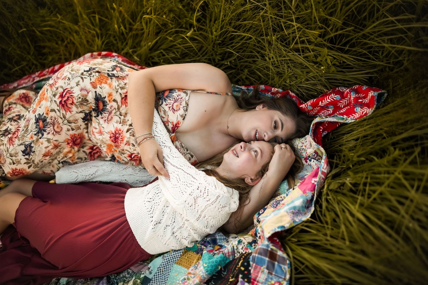 Loving couple resting together in tall grass during a romantic outdoor photoshoot.