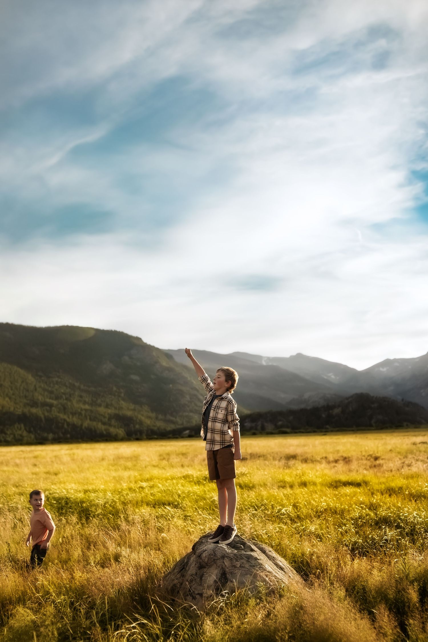 A joyful scene in a golden meadow with mountains in the background during sunset.