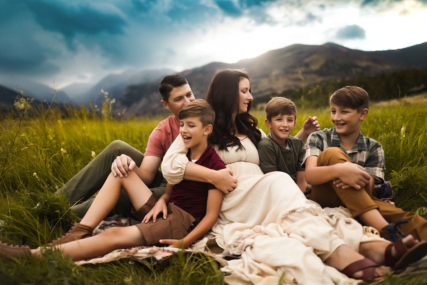 Group lounging together in a sunny mountain meadow during golden hour.