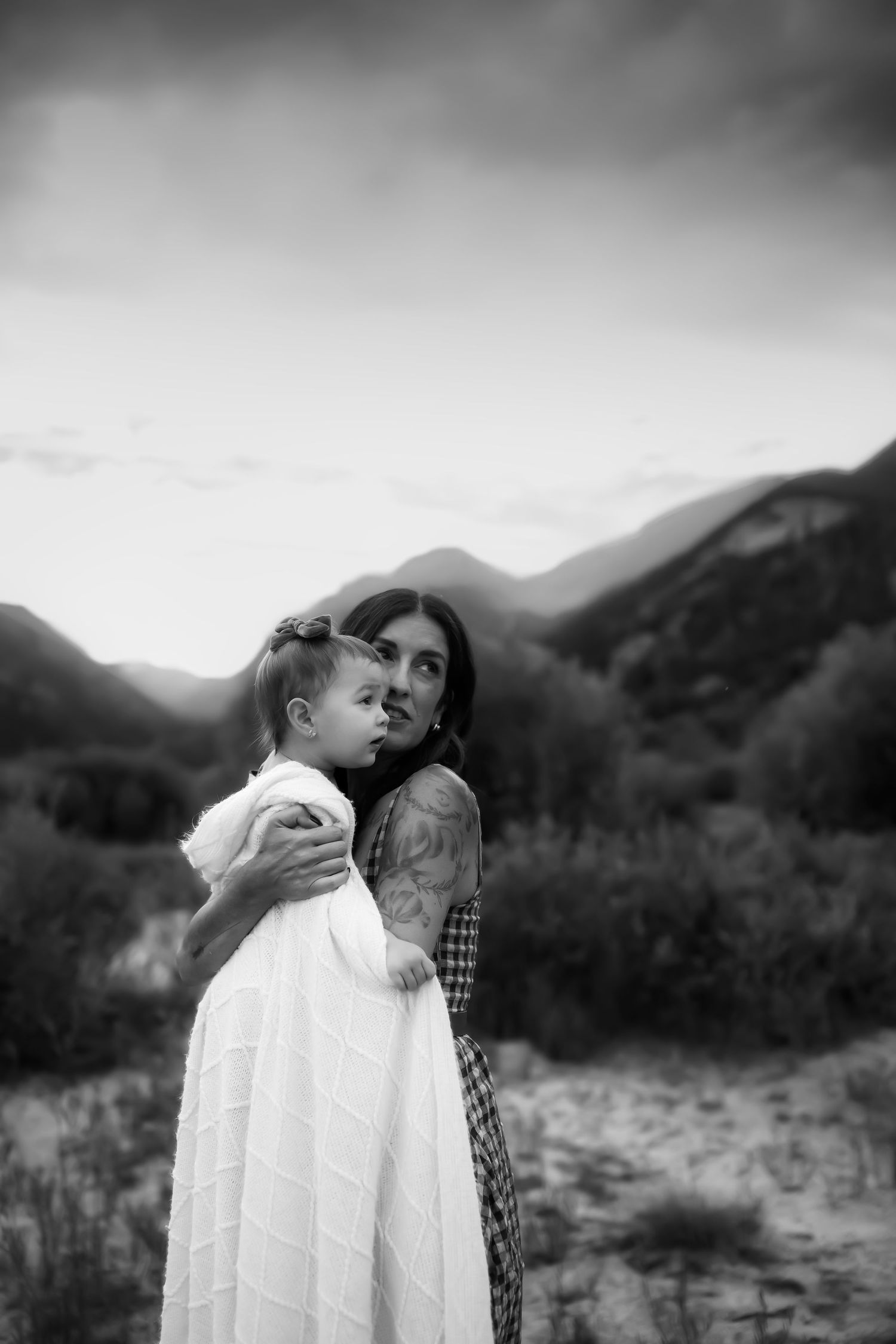 Black and white portrait against misty mountain landscape.