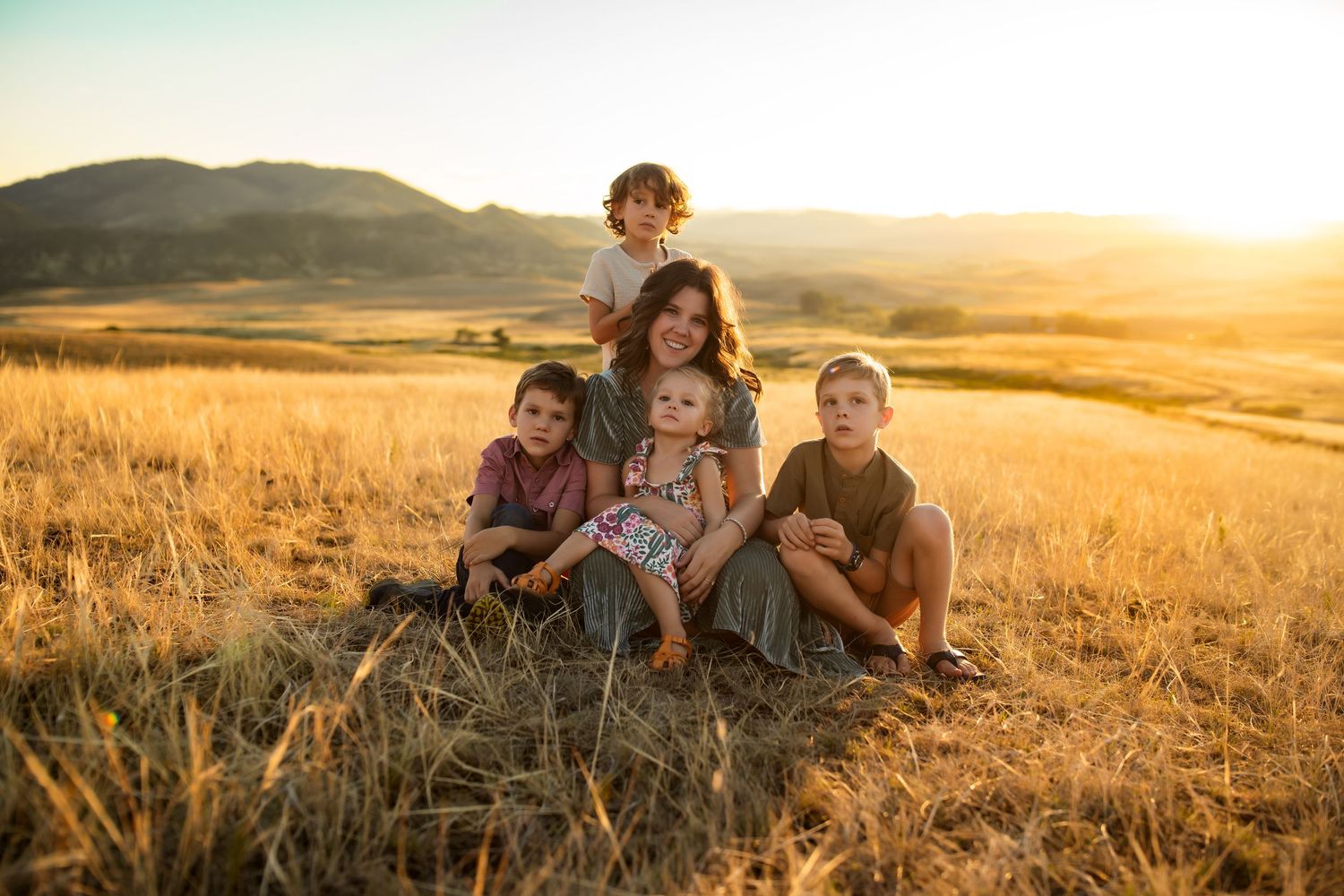 A group of people sitting in a field at sunset, enjoying the peaceful countryside scenery.