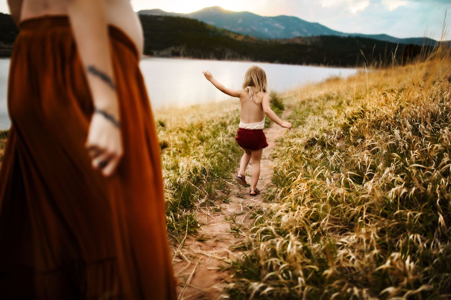 Person walking along a mountain trail with scenic valley views in the background.