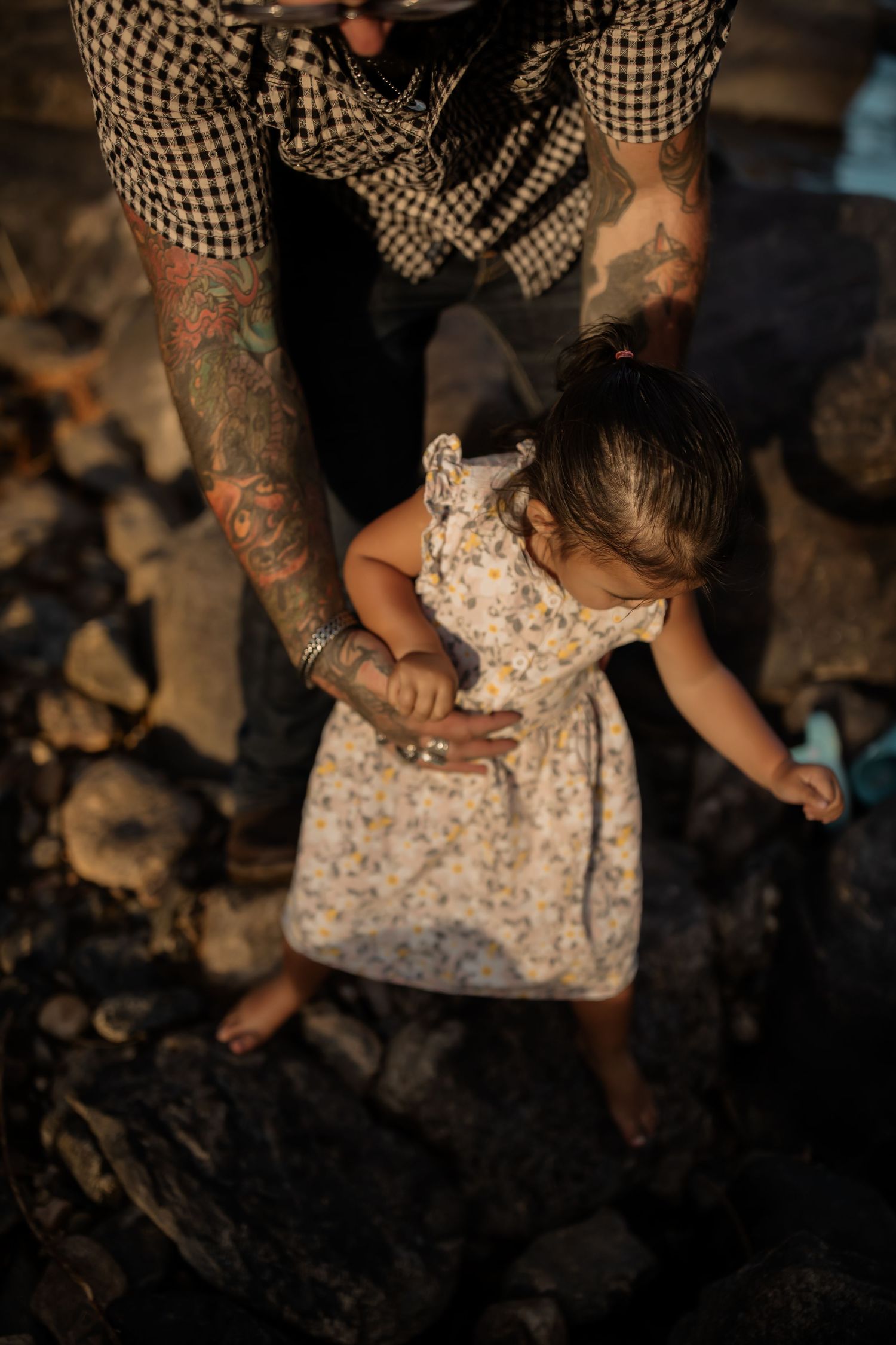 Overhead view of someone in checkered shirt and floral dress walking on rocky ground.