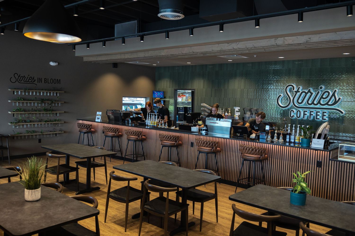 Modern Storles Coffee shop interior with bar seating, dark tables, and neon sign above the counter.