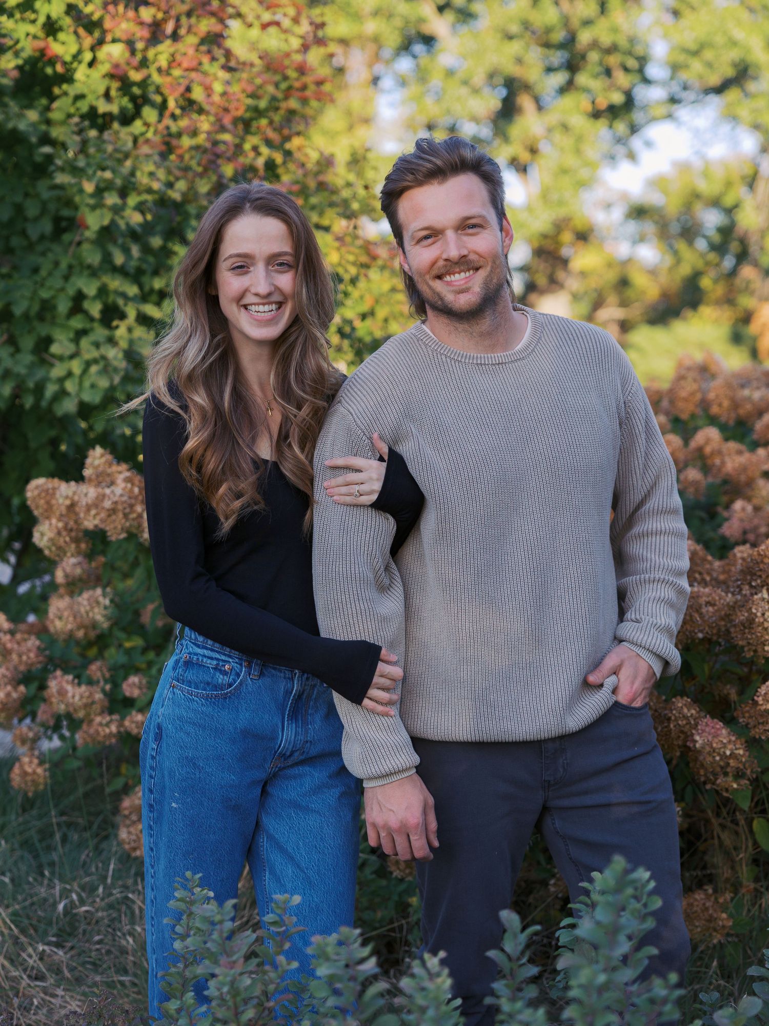 Playful couple photos in autumn with sweater and jeans against colorful foliage.