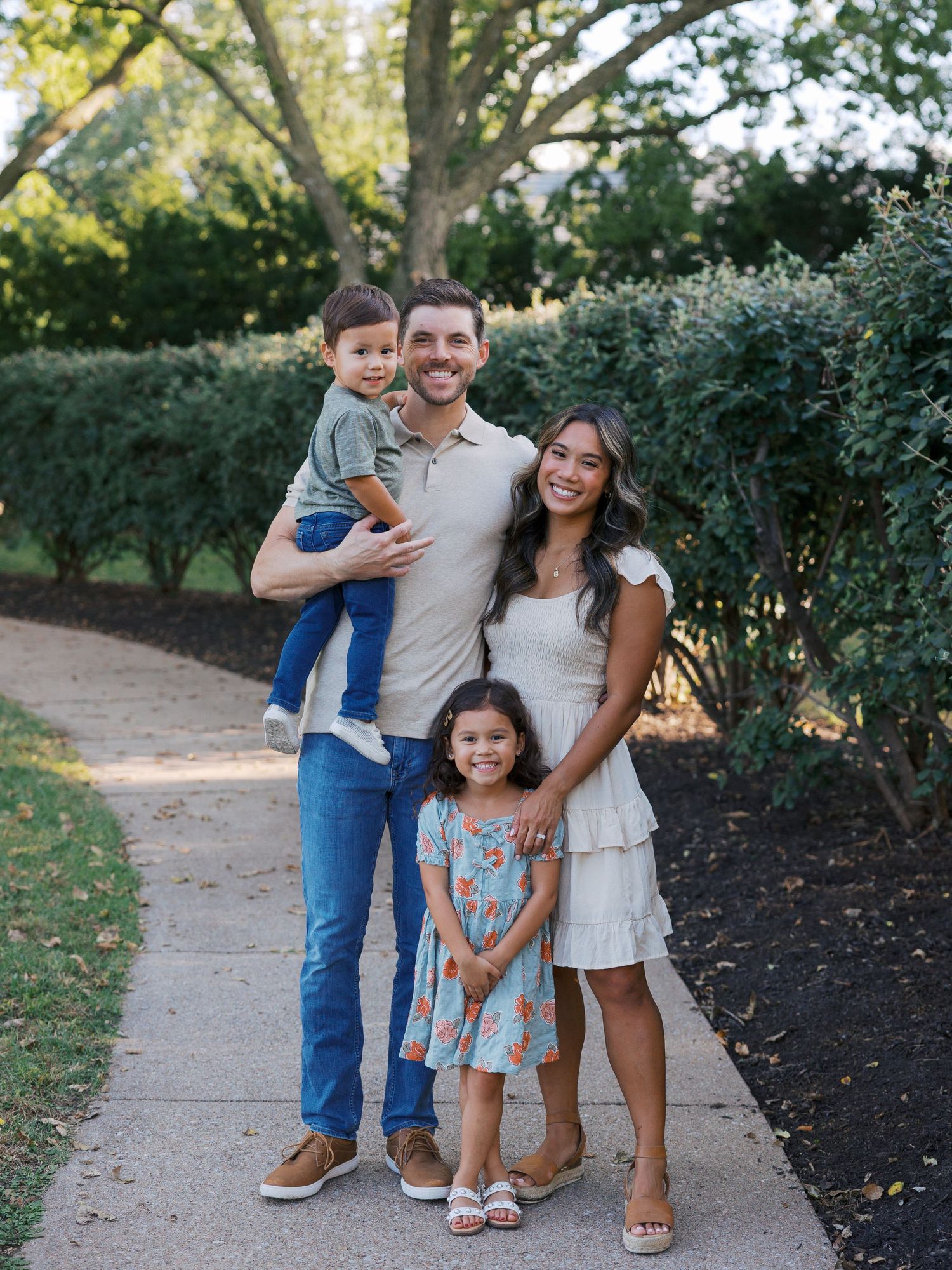 Casual family photos on a garden path with coordinated neutral and blue outfits.