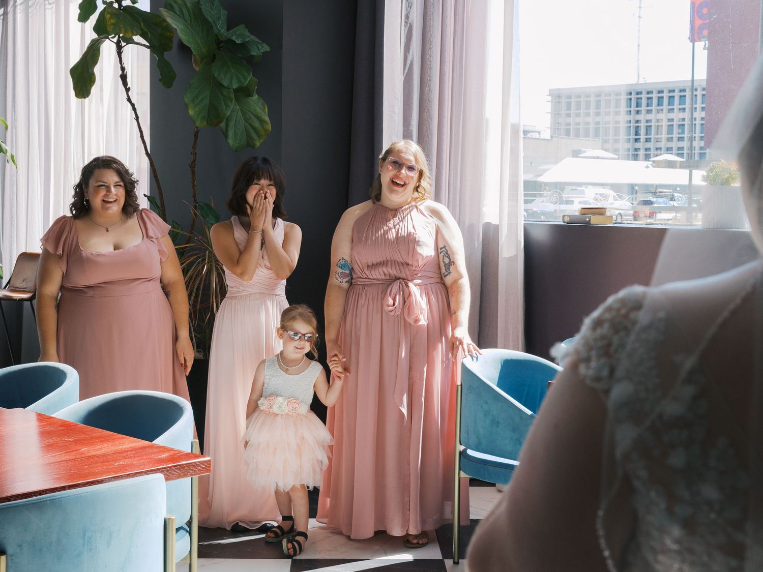 Bridesmaids in pink dresses react emotionally as bride reveals her wedding gown in a modern Las Vegas venue.