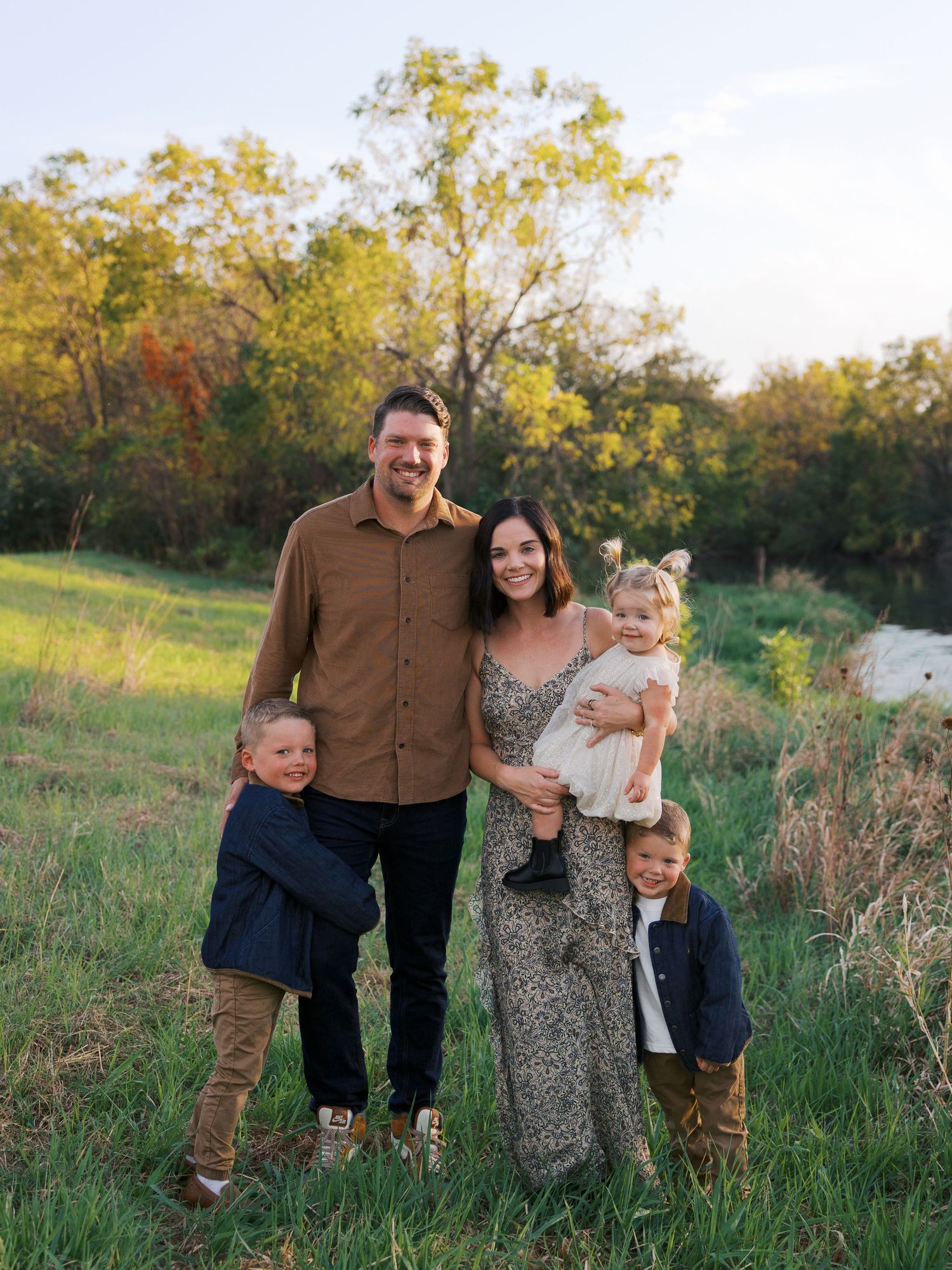 Family enjoying a candid moment together in a sunlit field during golden hour.
