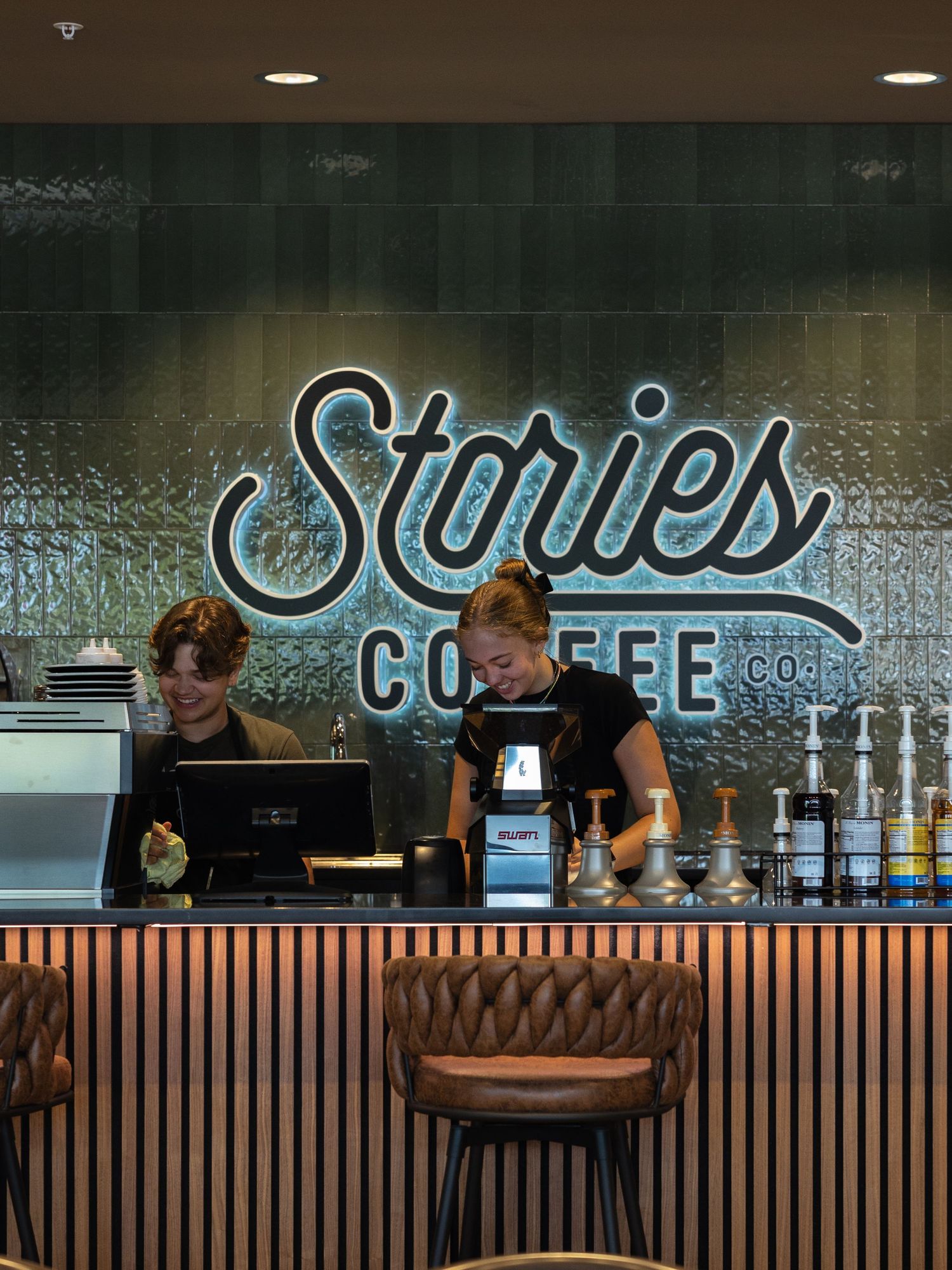 Modern coffee shop interior with blue neon signage and wooden paneled counter.