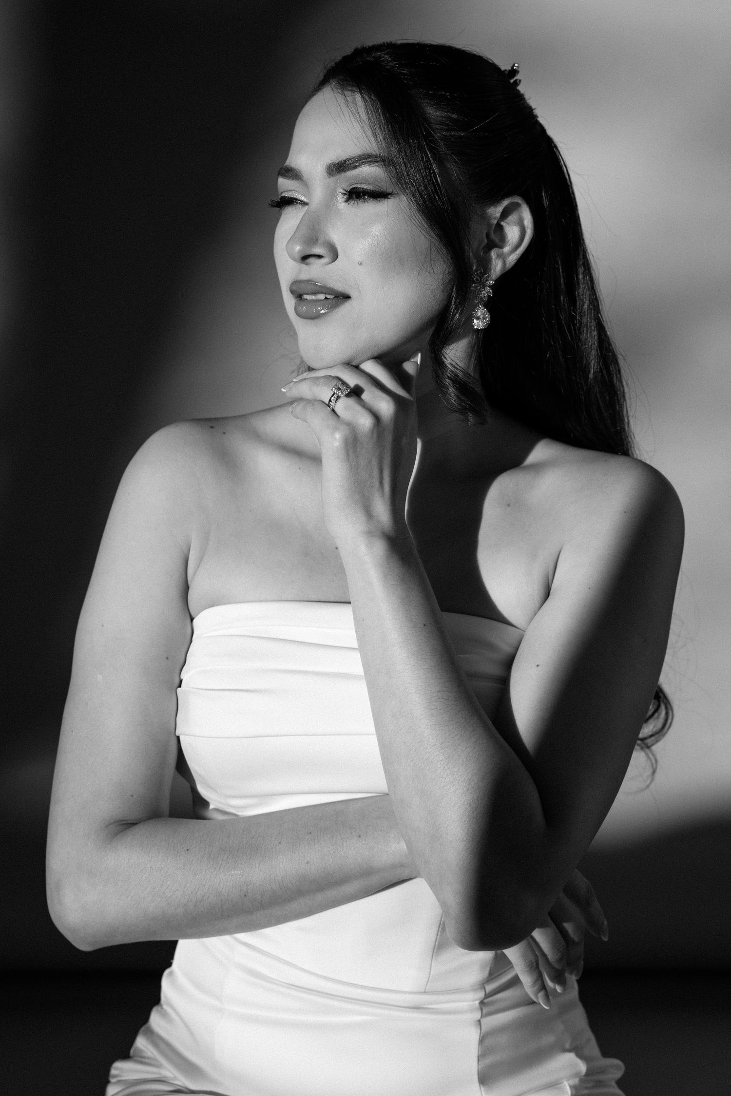 Artistic black and white portraits of woman in white top with dramatic lighting.