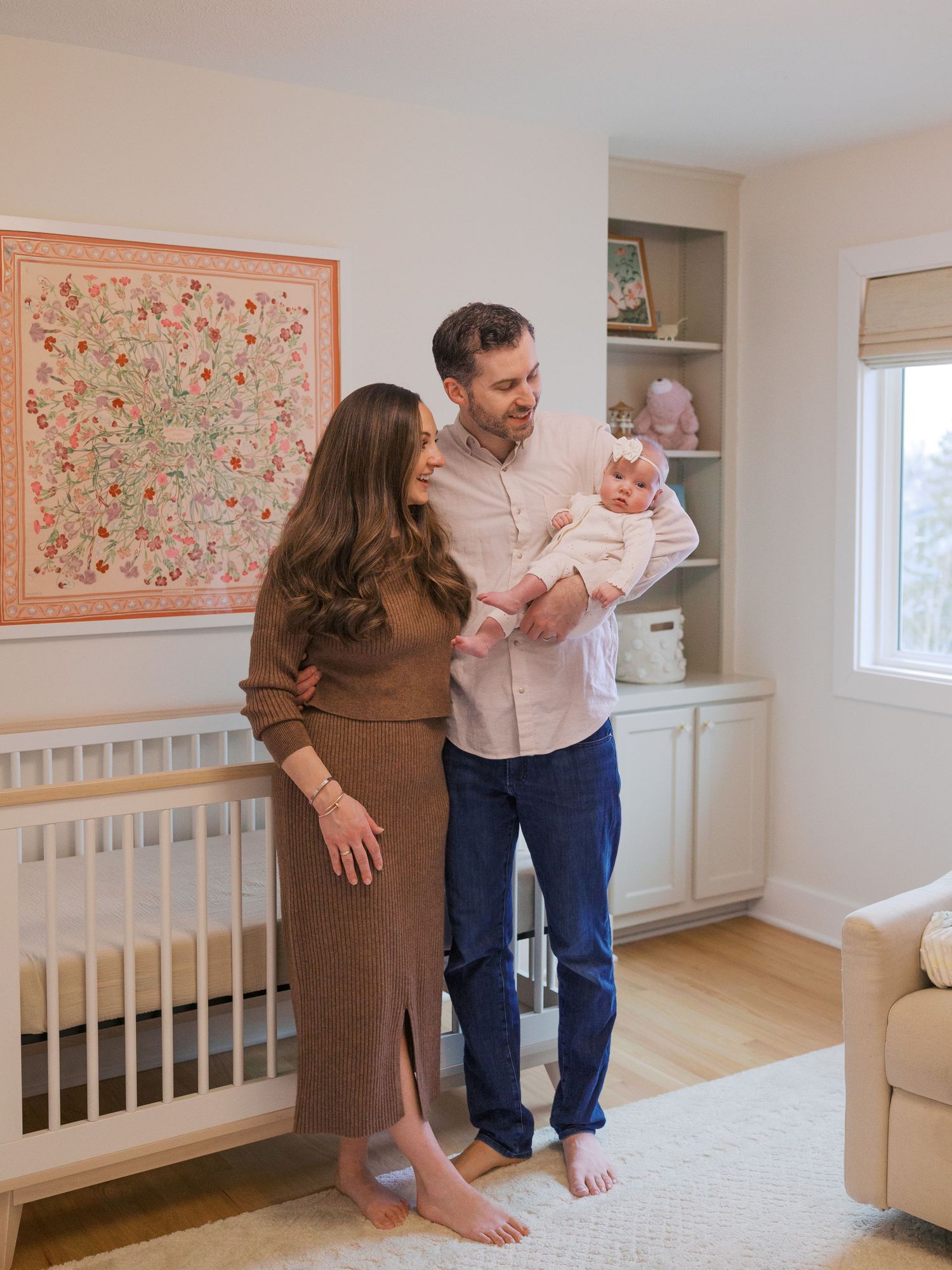 A nursery room with white walls, floral artwork, and a white crib.