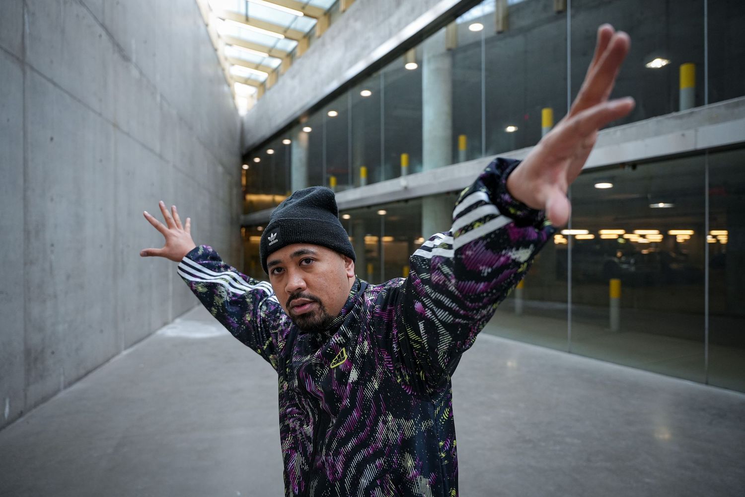 Person in patterned jacket strikes dynamic poses against concrete urban backdrop.