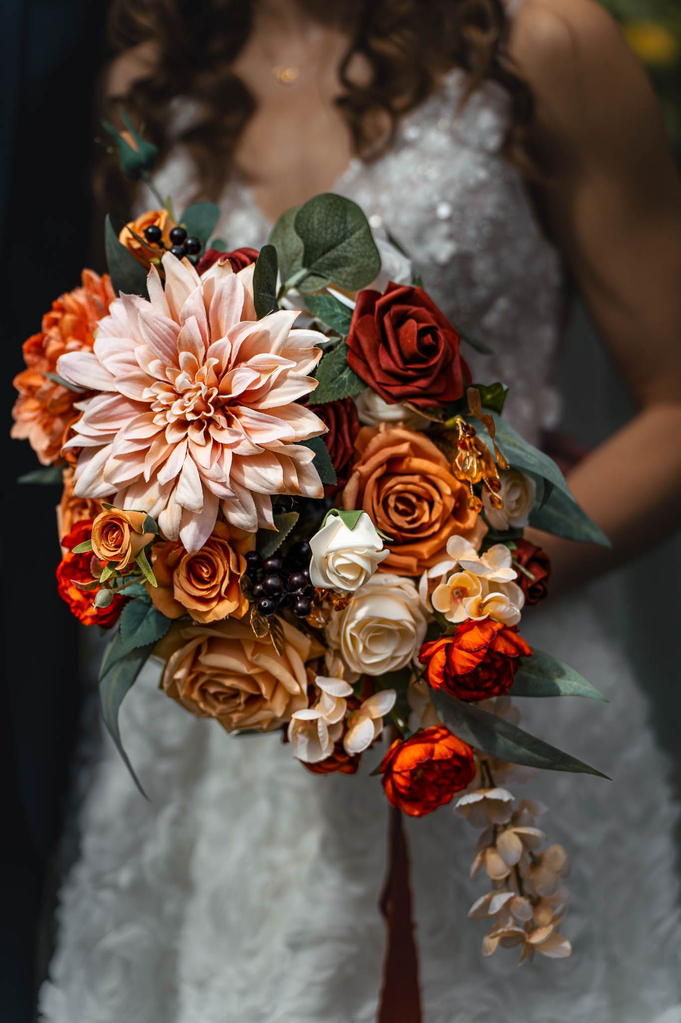 Fall-themed bridal bouquet with orange dahlias, roses and mixed flowers.