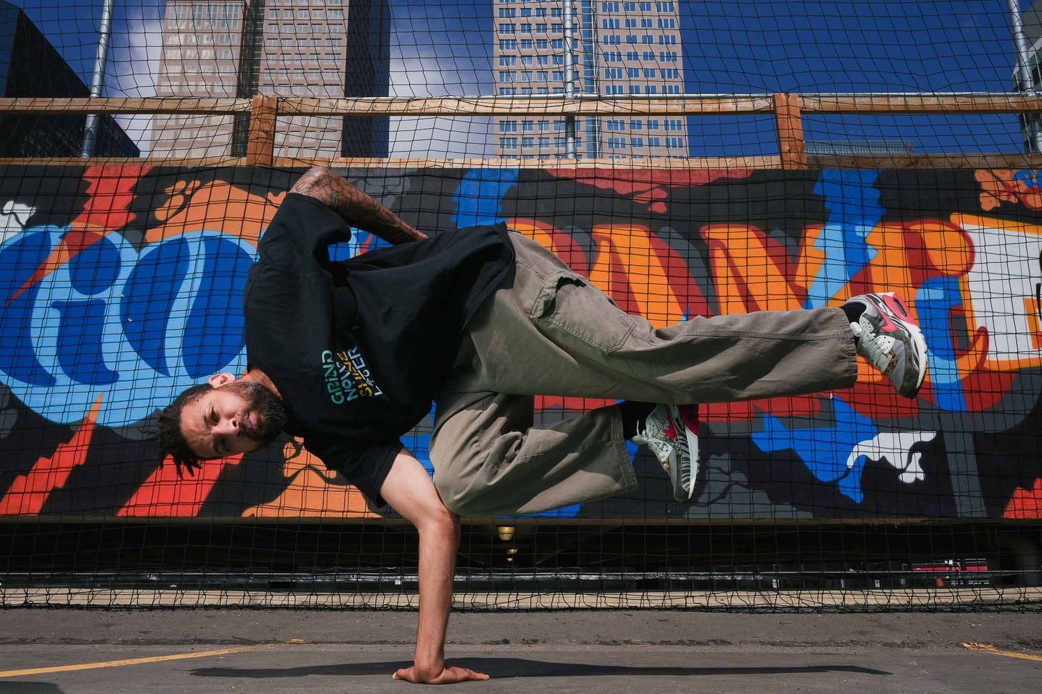Athletic performer executes sideways balance move along urban barrier.